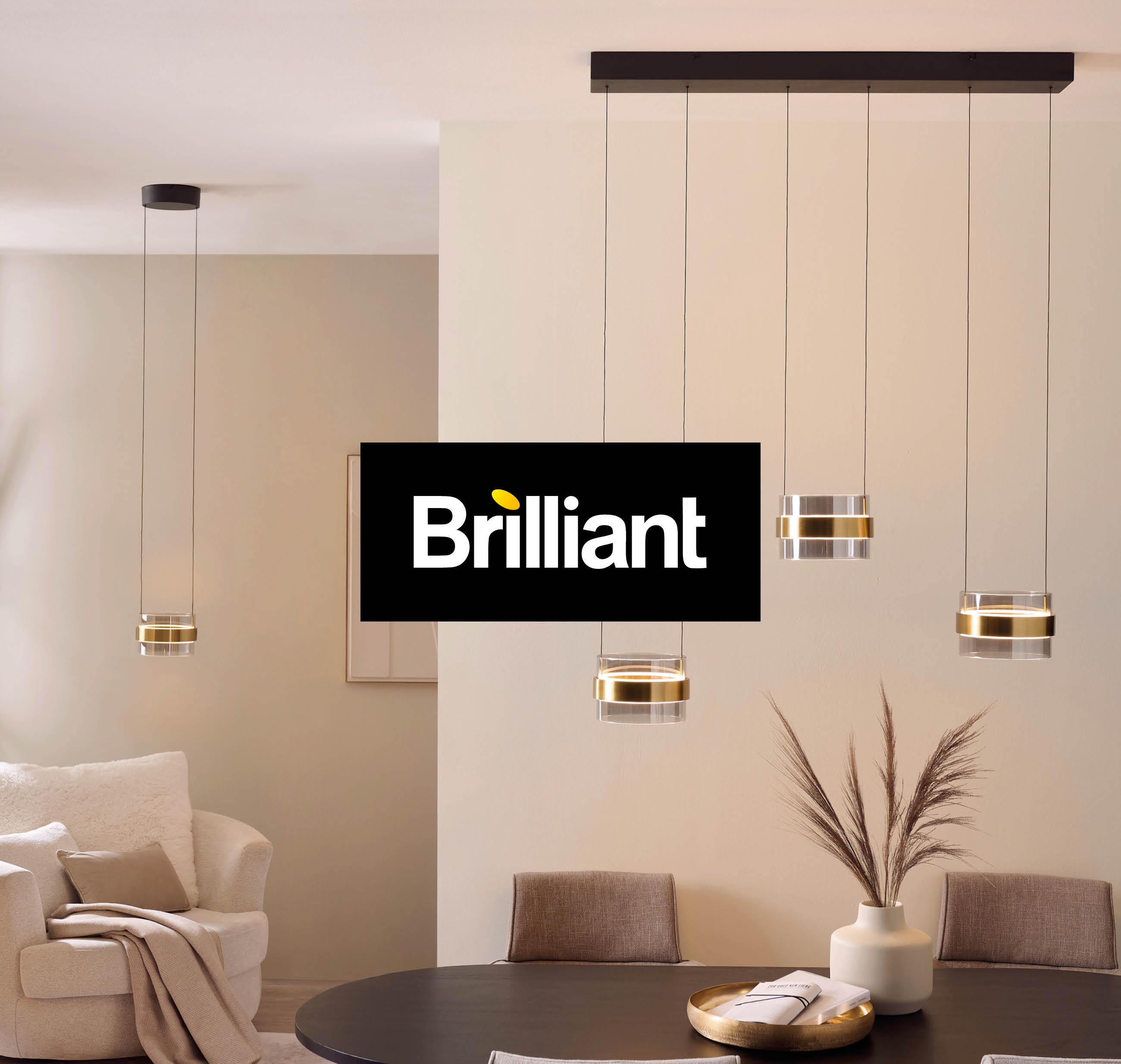 Helles, modernes Wohnzimmer mit Designer-Hängelampen, gemütlichem Sessel, Dekovase mit Trockenpflanzen und dem Logo „Brilliant“ in der Mitte.