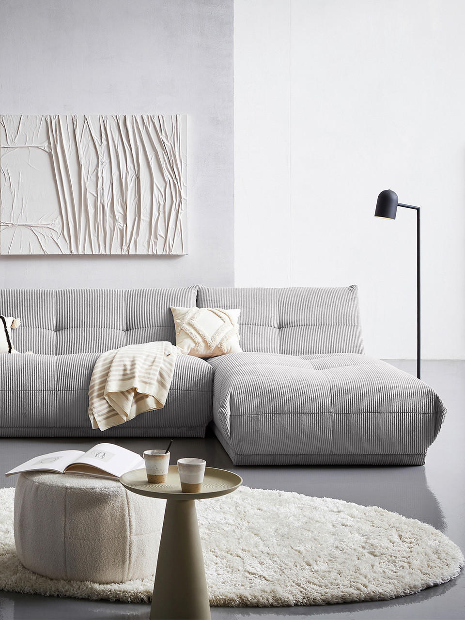 graue Couch mit weißer Wand, Teppich und Tisch