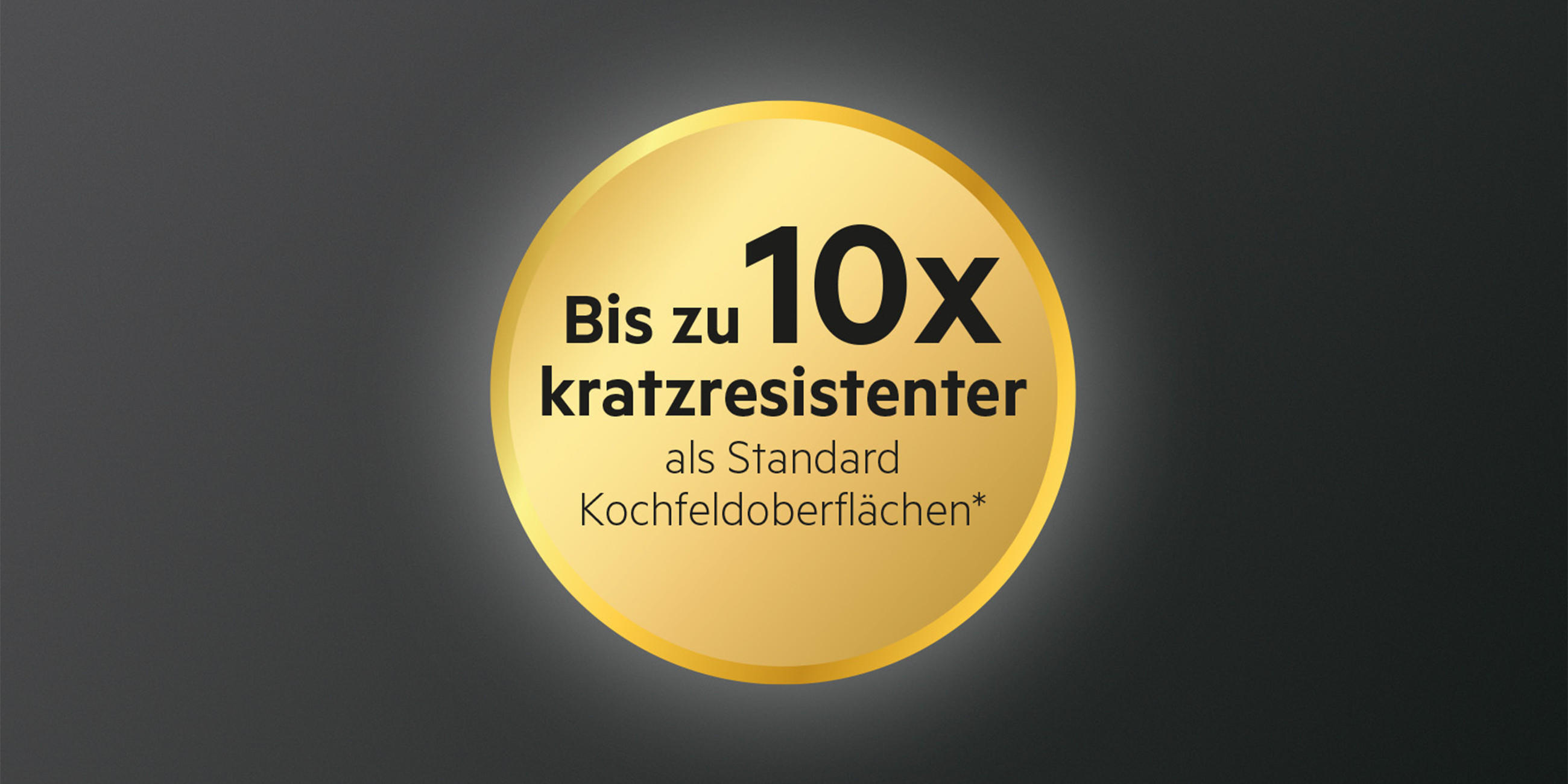 Goldenes Hinweis-Siegel mit der Aufschrift „Bis zu 10x kratzresistenter als Standard Kochfeldoberflächen*“ auf dunklem Hintergrund.