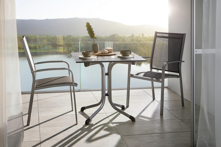 Balkon-Set bestehend aus einem quadratischen Metalltisch mit gebogenen Beinen und zwei modernen, schwarzen Netzstühlen mit Armlehnen