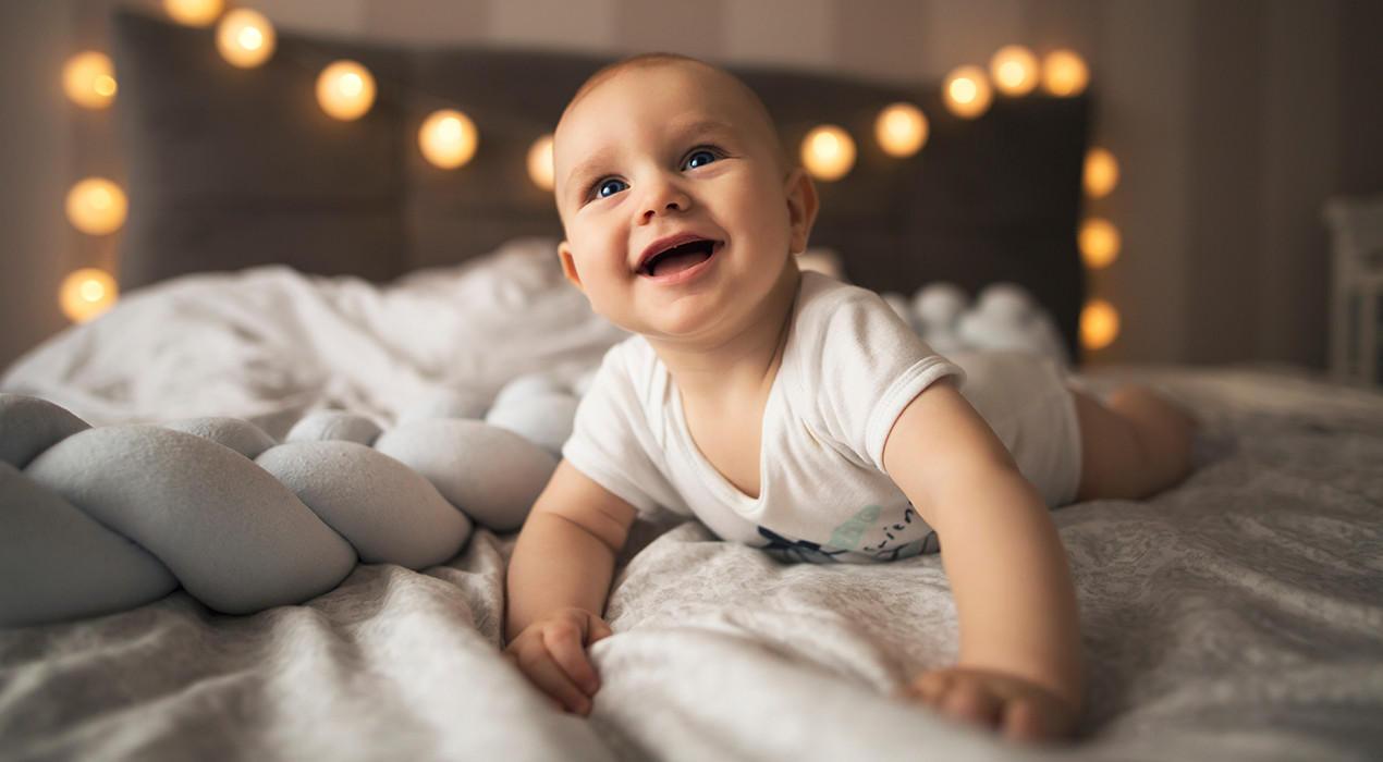 Baby grabbelt glücklich auf Bett
