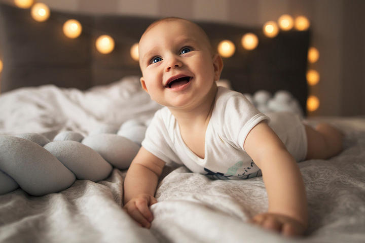 Baby grabbelt glücklich auf Bett
