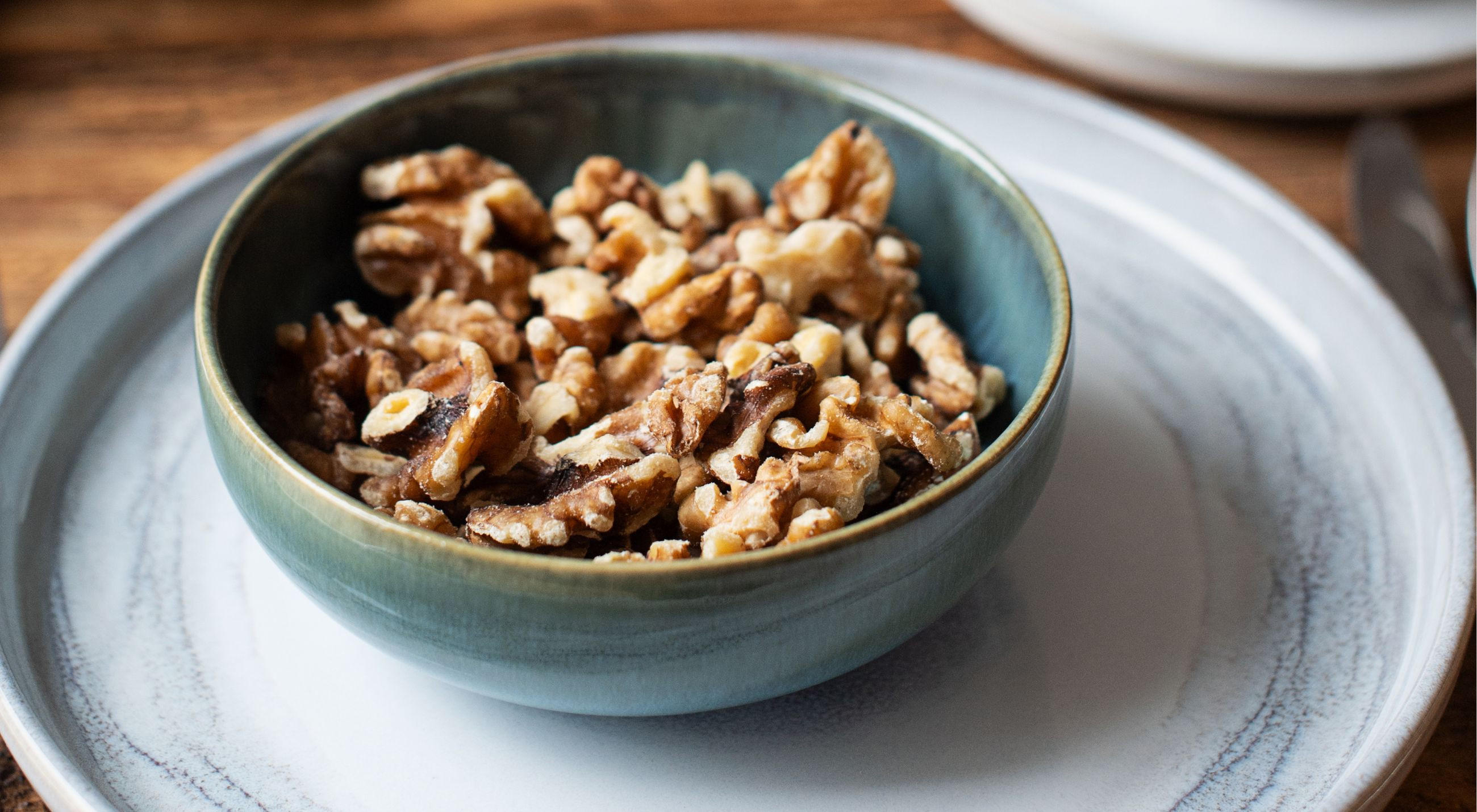 Eine Schüssel der Marke GIPFELSTÜCK mit Walnüssen auf einem Holztablett.