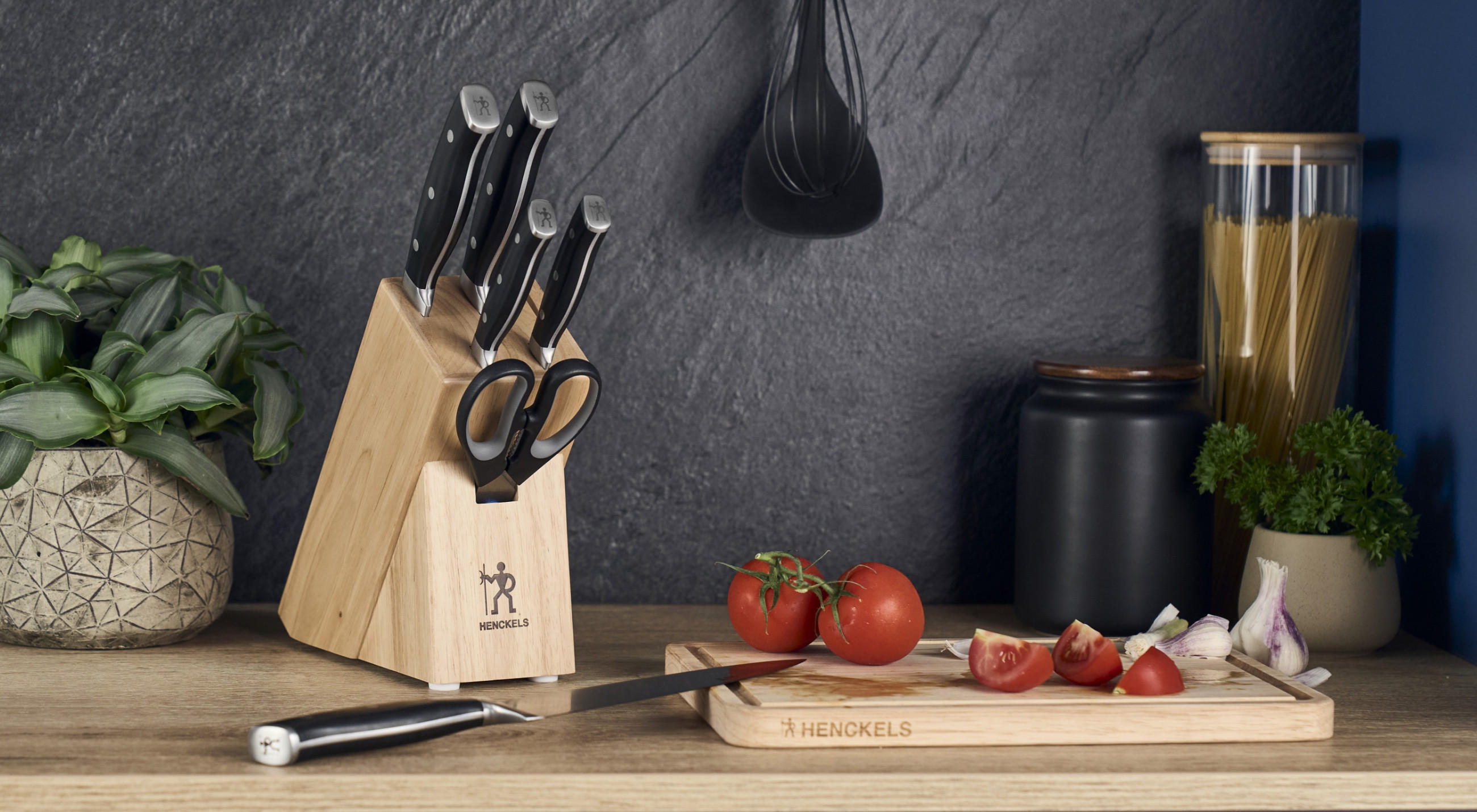 Nahaufnahme von Arbeitsplatte mit Messerblock von Henckels by Zwilling mit hochwertigen Küchenmessern und Schneidebrett aus Holz.