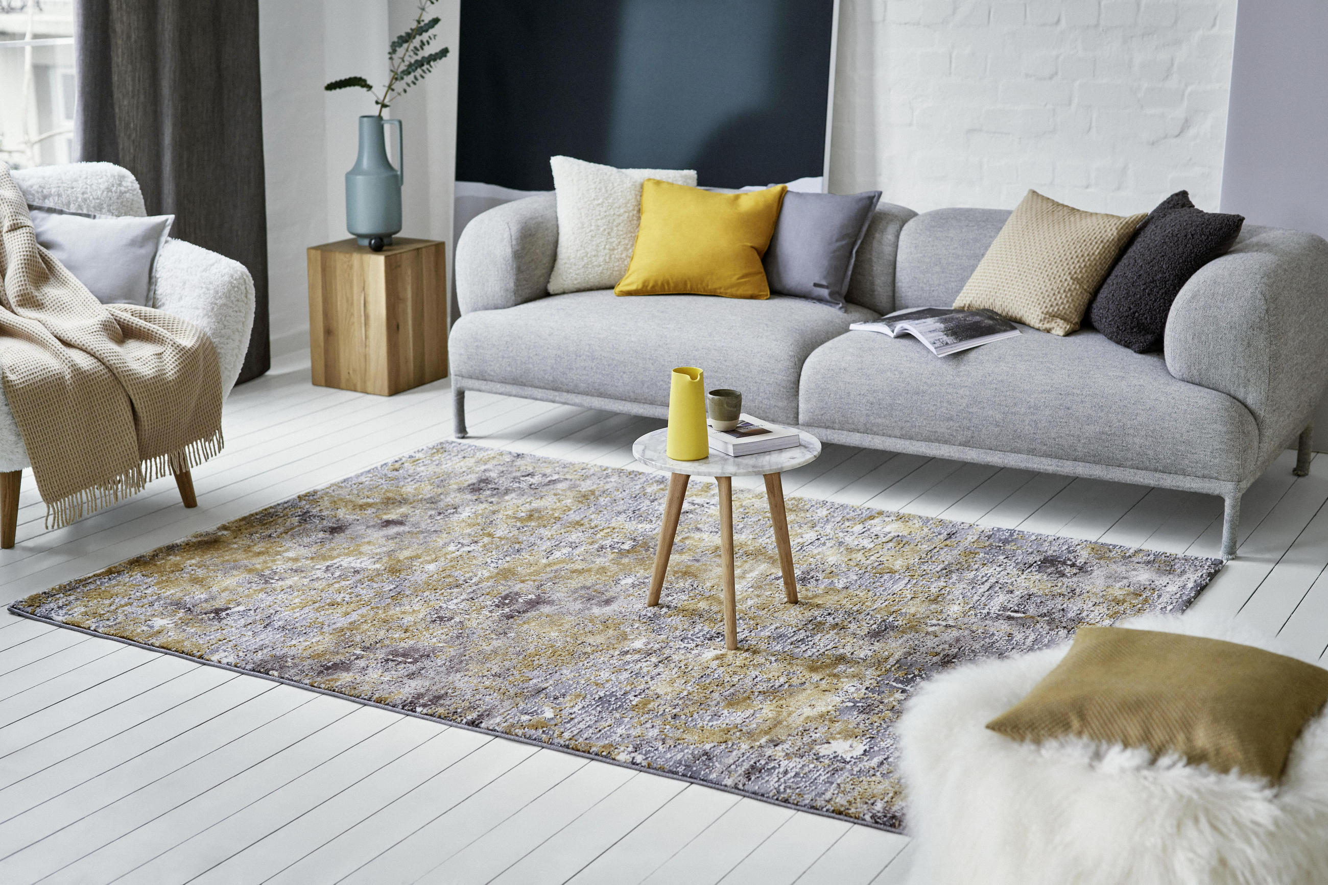 Šedá pohovka, barevné polštáře a vintage koberec