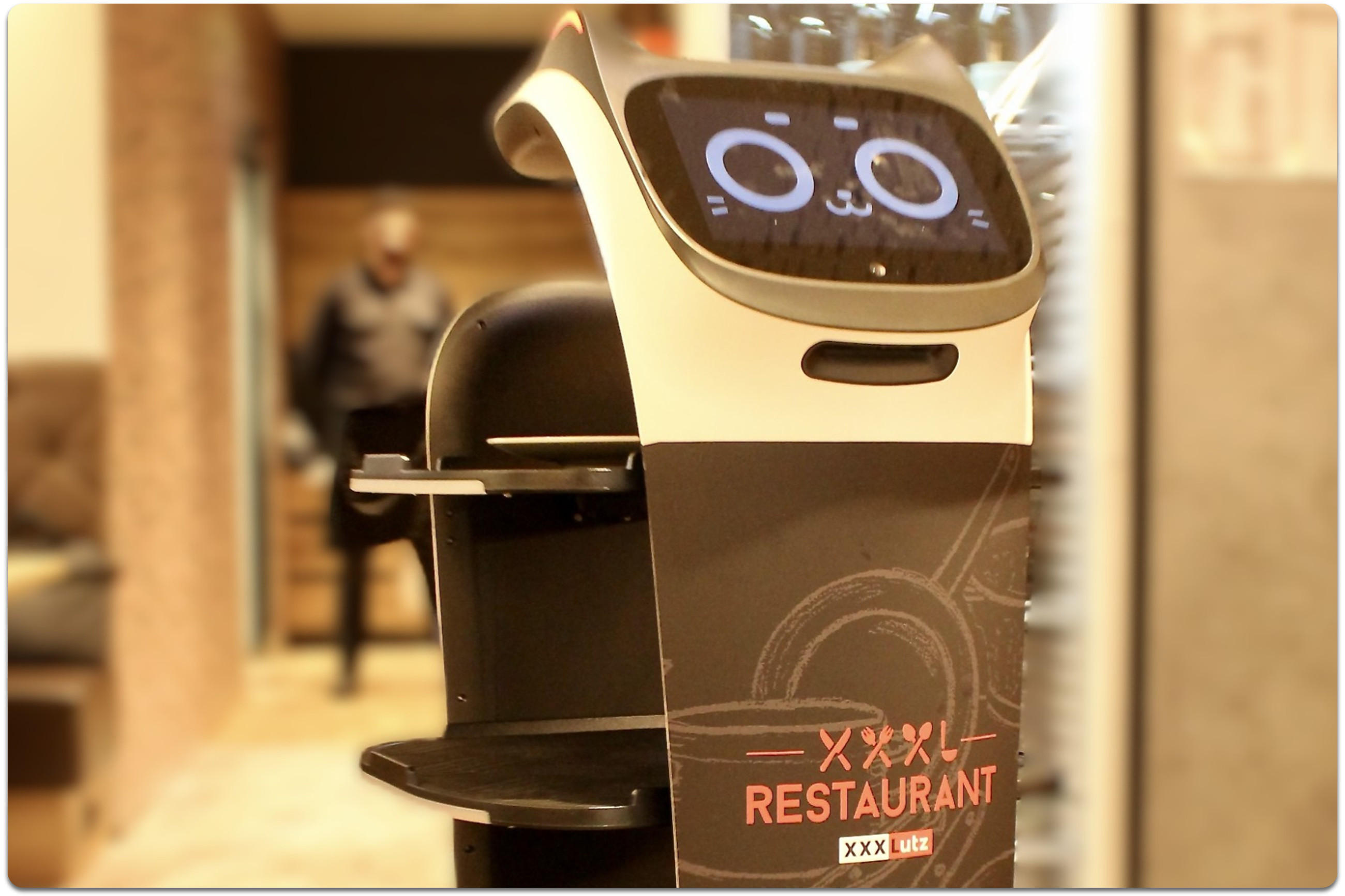 Schwarzer Serviceroboter aus dem Restaurant in Rangsdorf mit Display, auf dem ein Katzengesicht sichtbar ist.