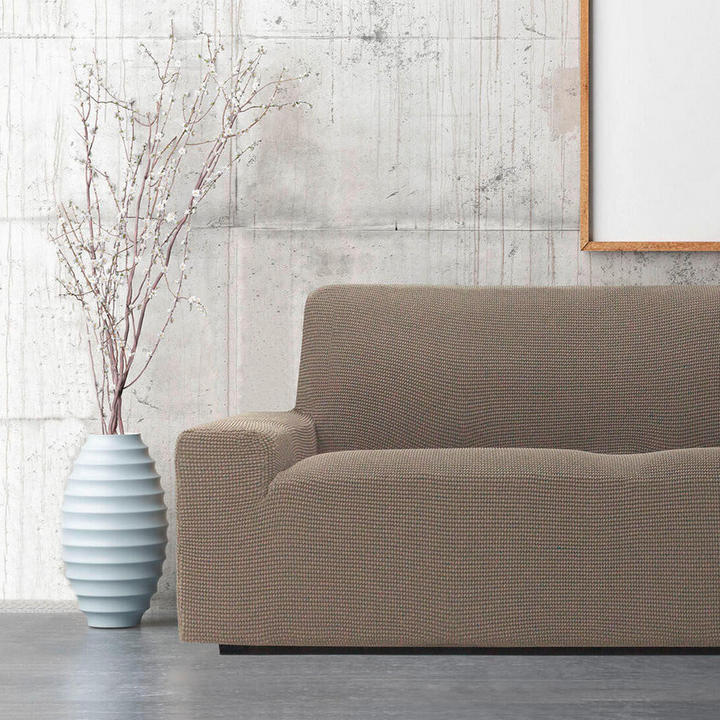 Predstavljeni so kavč s prevleko in vaza, ki sta umeščena pred steno, kar ustvarja prijetno vzdušje.