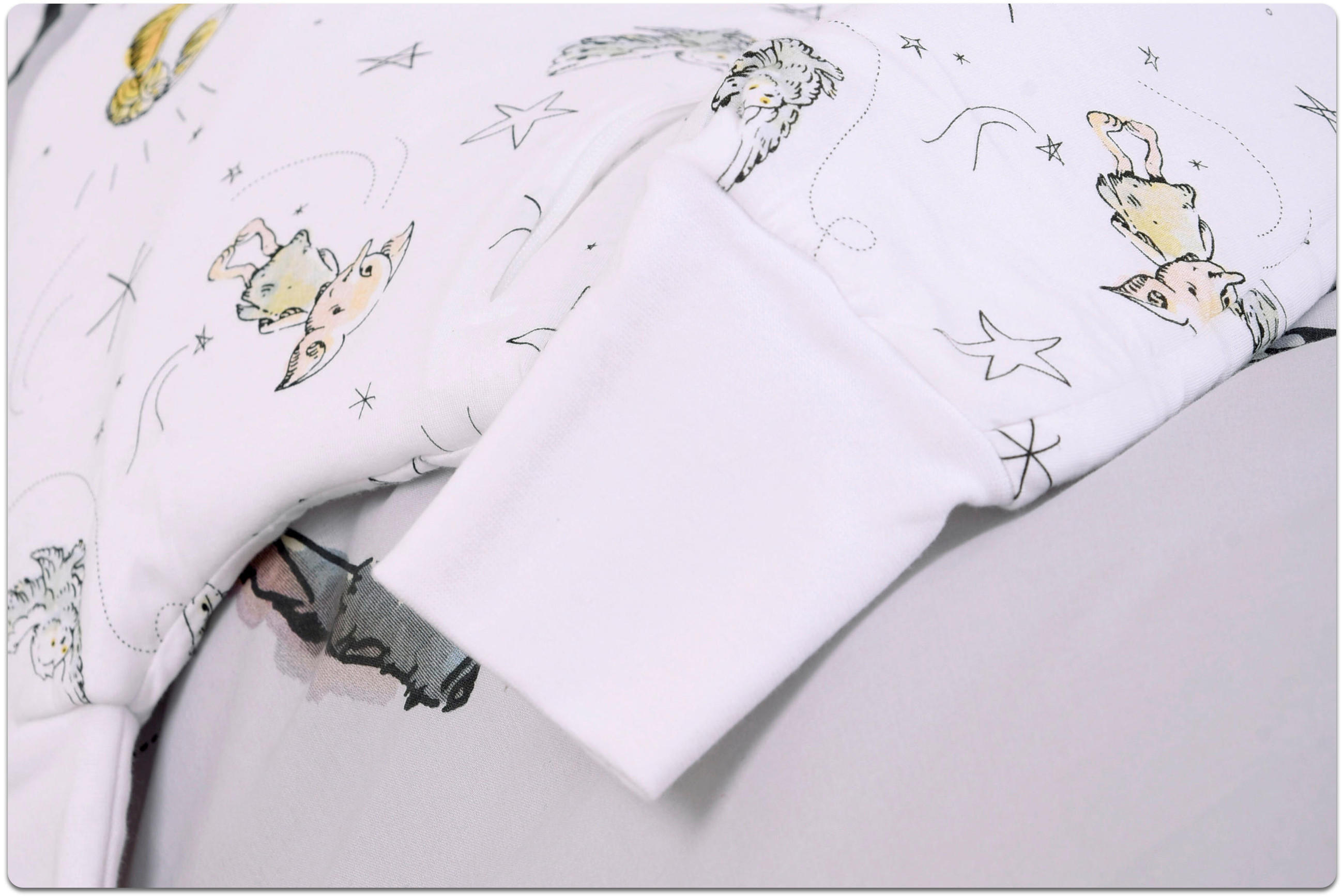 Detailaufnahme eines weißen Babyschlafsacks mit Sternenmuster in grau und einer Figur aus Harry Potter. Der Schlafsack hat offene Füße und verstärkte Jersey‑Bündchen am Fußbereich