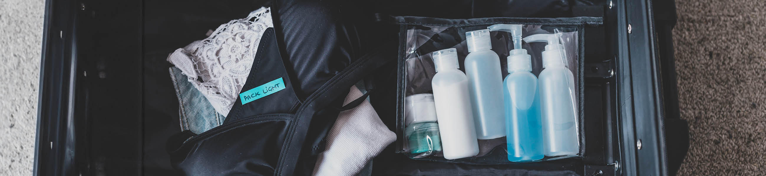 Koffer mit einer Tasche, die Pflegeprodukte für das Handgepäck zeigt, ideal für Reisen.