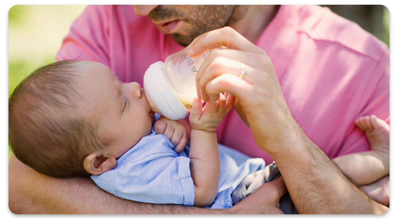 Papa mit Baby im Arm, gibt die Flasche