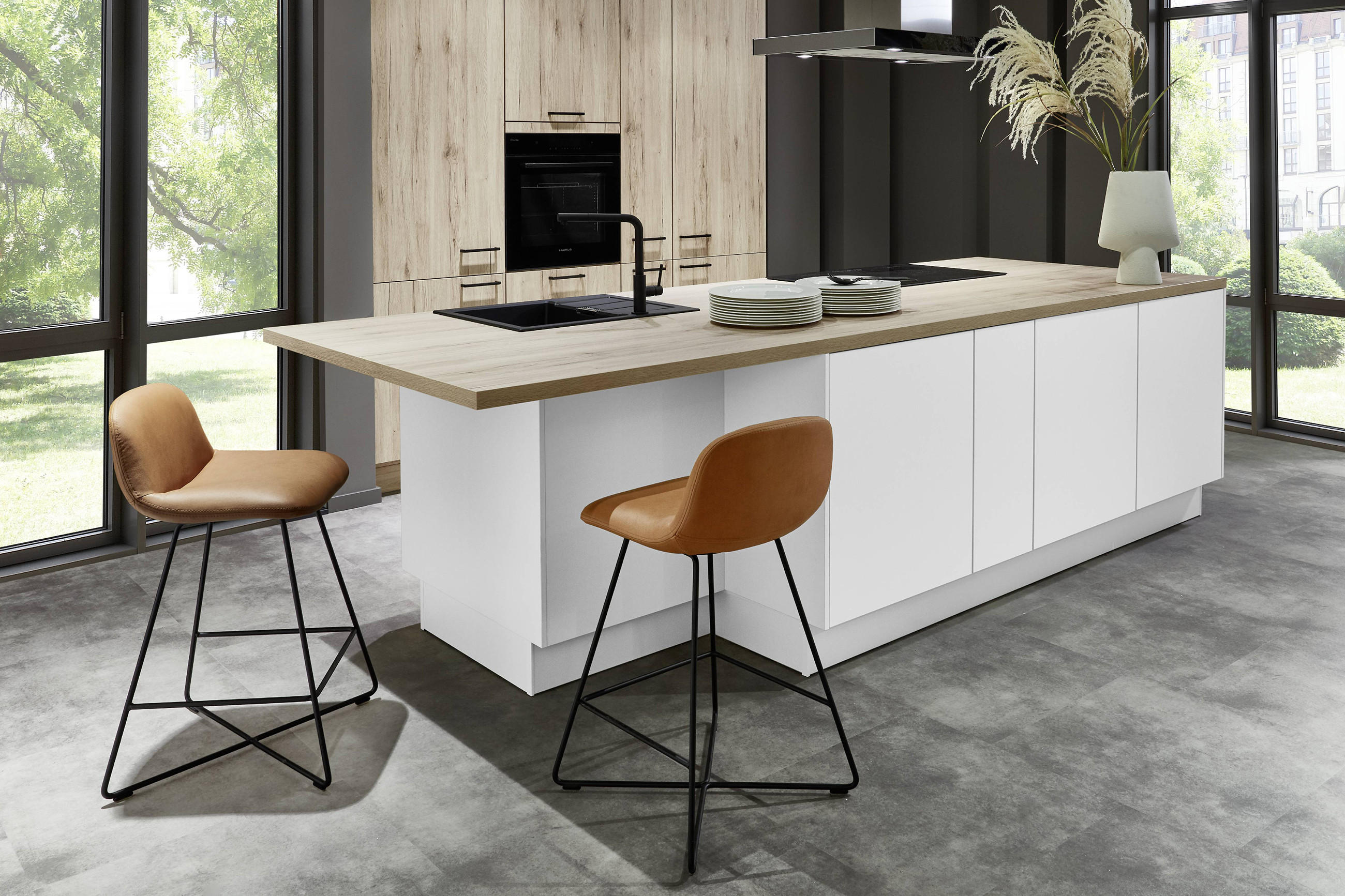 Moderne Küche in weiß, mit hellem Holz und zwei stilvollen Hockern an der Kochinsel. 