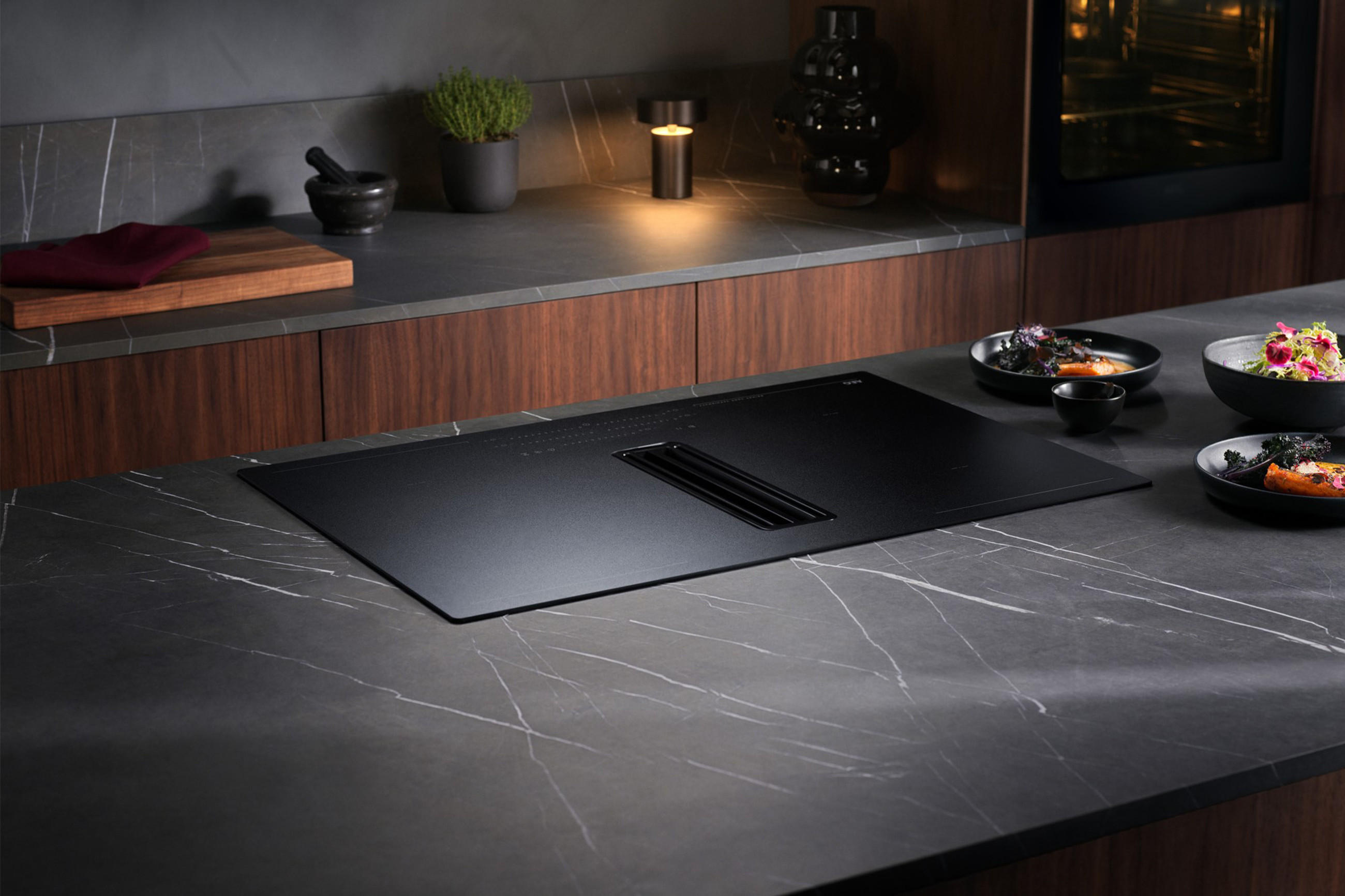 Moderne Küche mit schwarzem Arbeitsplatten, eleganten AEG Geräten und minimalistischer Einrichtung.