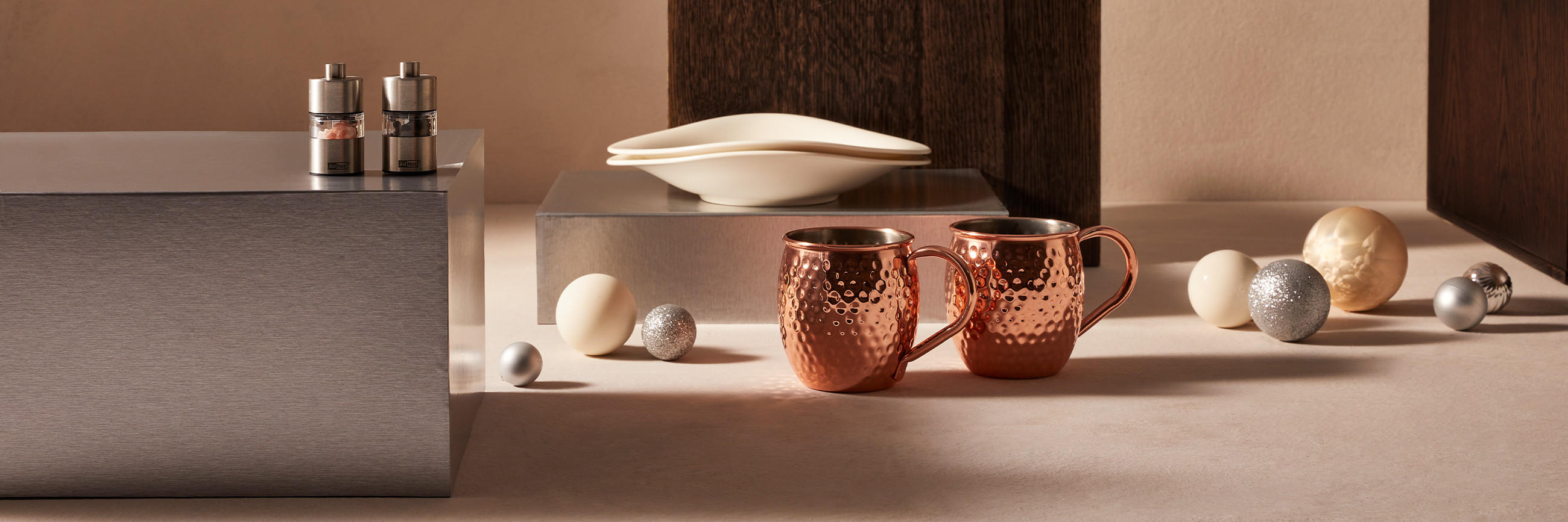 Salz- und Pfefferstreuer und zwei goldene Tassen in weihnachtlicher Atmosphäre mit Christbaumkugeln