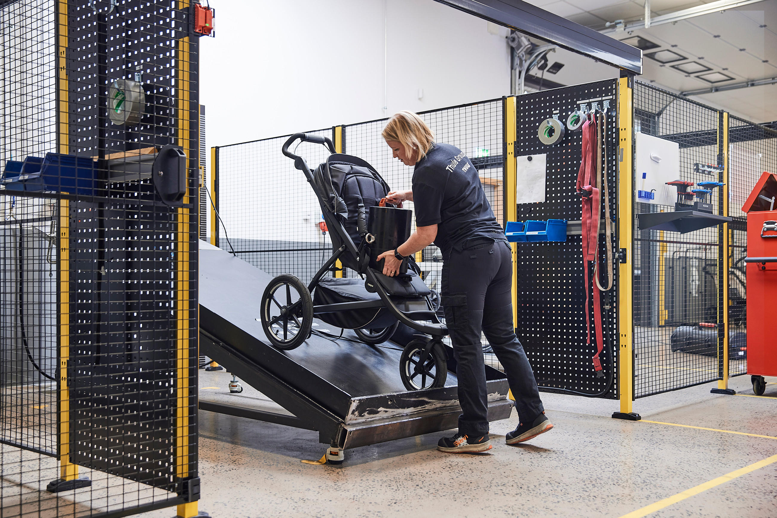 Mitarbeiter im Thule Test Center in Schweden prüft einen Kinderwagen auf einer schrägen Prüfplattform