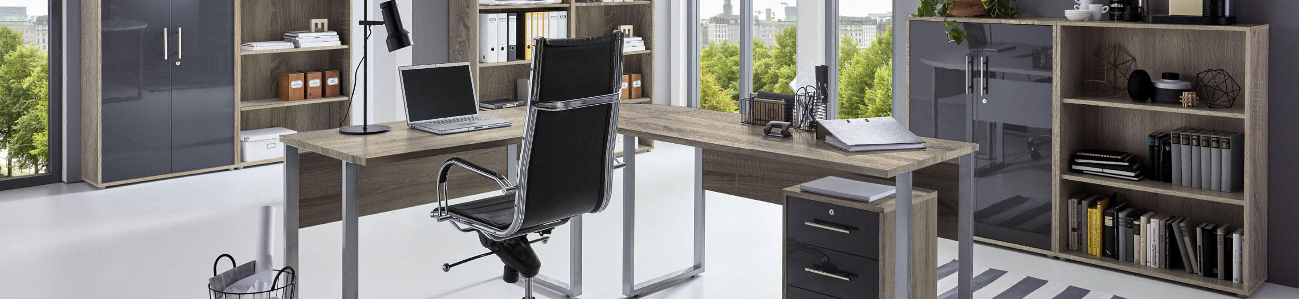 Modernes Büro mit Eckschreibtisch, Bürostuhl, Rollcontainer und Aktenschränken aus Eiche, Anthrazit und Hochglanz vor großen Fenstern