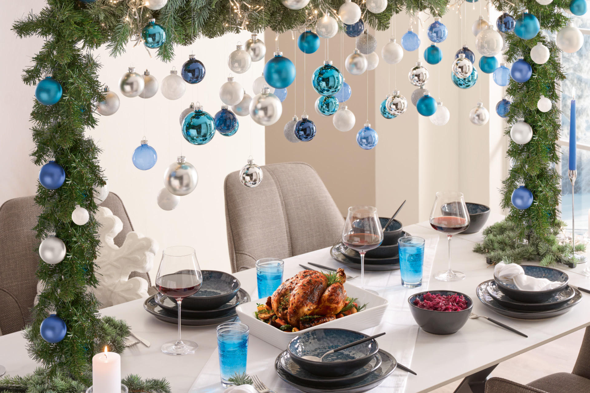 Gedeckter weißer Esstisch mit schwarzem Service; Tischdeko Weihnachtskranz mit blauen & weißen Kugeln