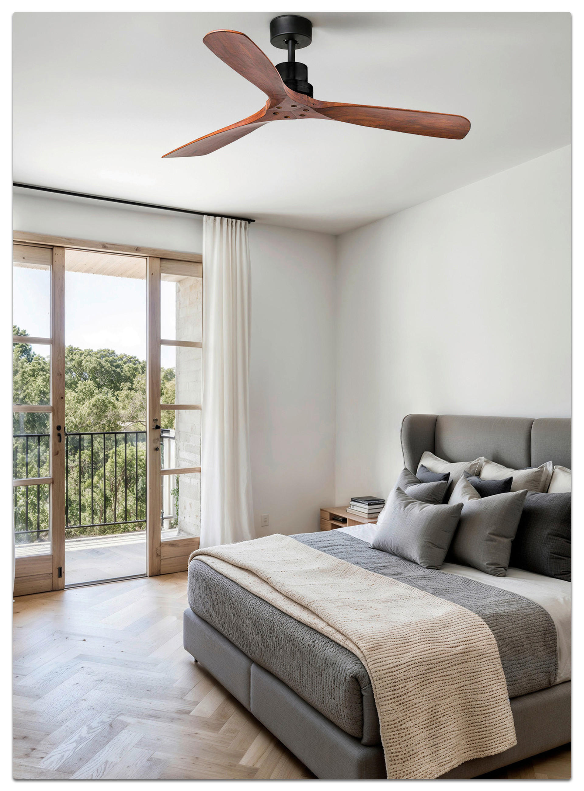 Modernes Schlafzimmer mit Deckenventilator, großem Bett und Zugang zum Balkon mit Blick ins Grüne.