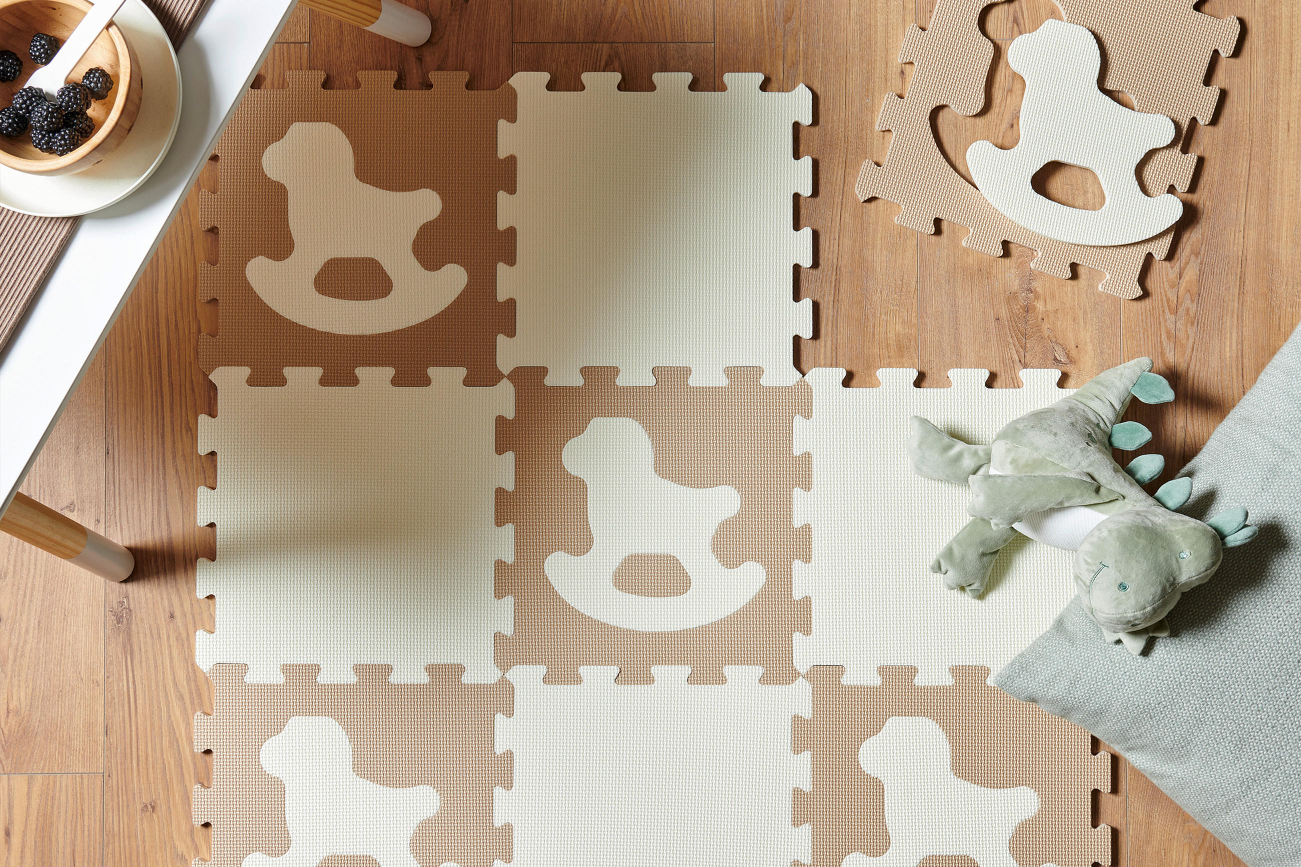 Puzzlematte in braun auf dem Boden mit einem Kuscheltier in grün daneben