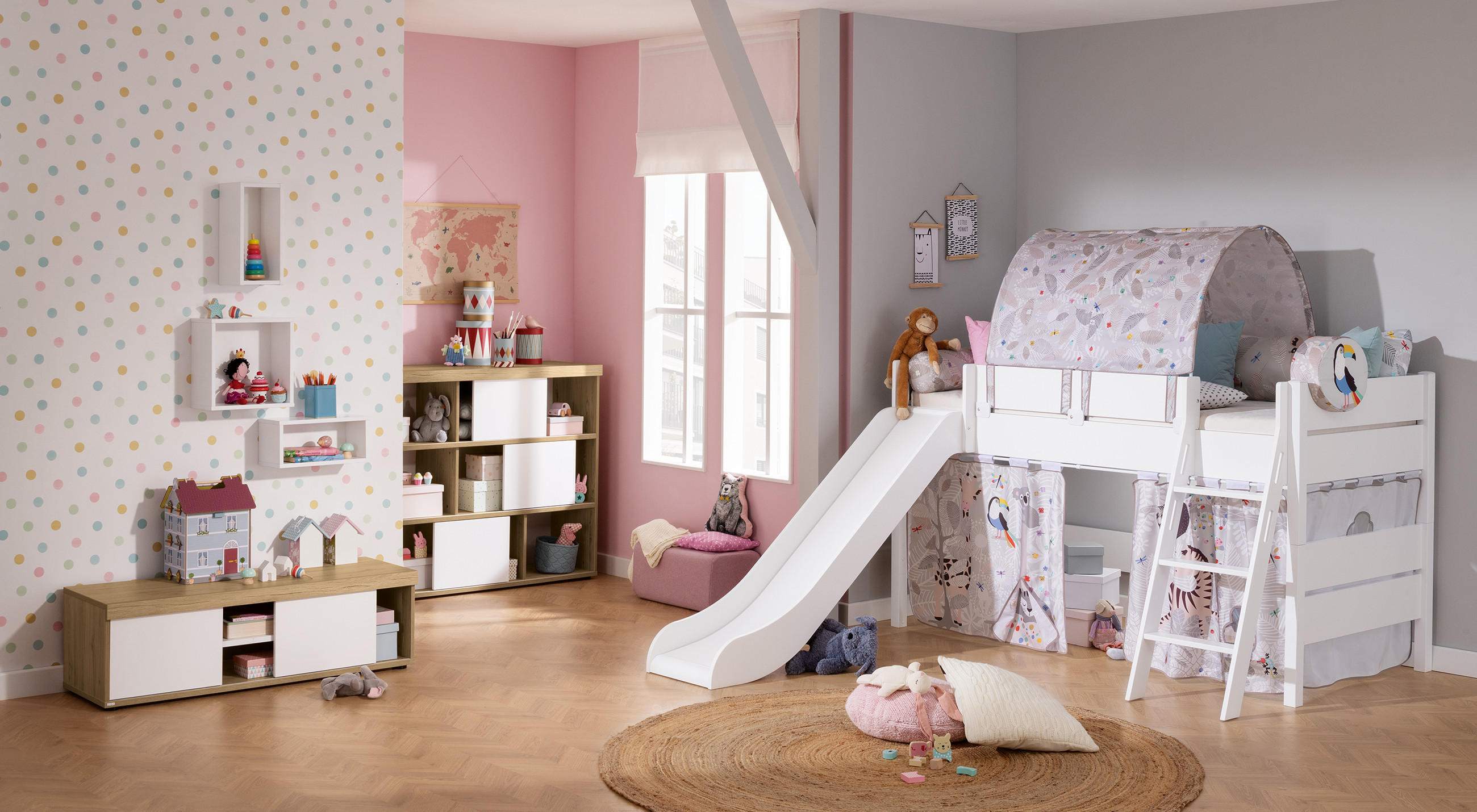 Kinderzimmer mit Hochbett inklusive Rutsche, Spielzelt und Leiter sowie Regalen mit Spielzeug vor einer gepunkteten Wand.