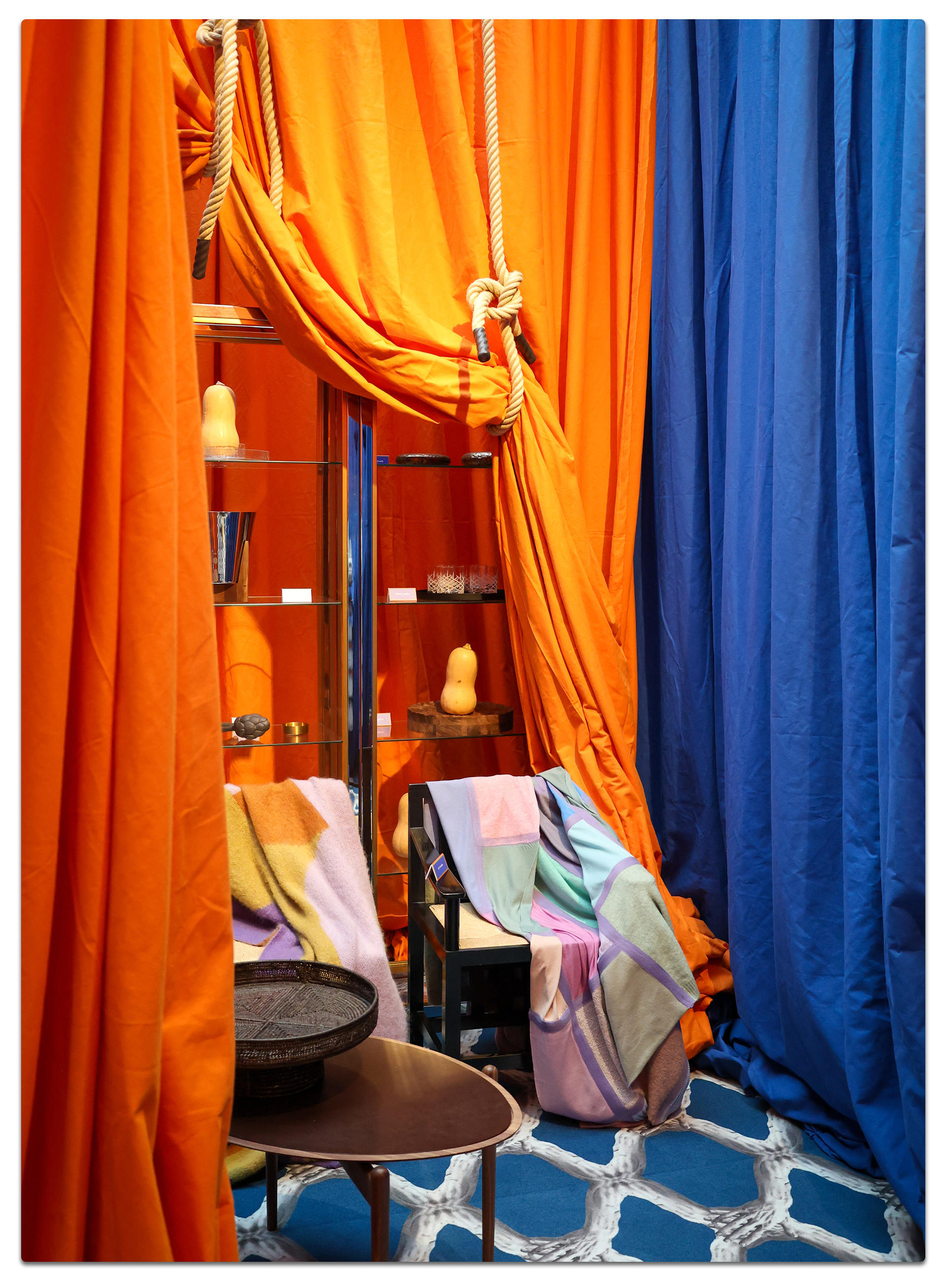 Ein Raum mit einem blauen Teppich und orangefarbenen Vorhängen, gestaltet für die Ambiente Messe 2025.