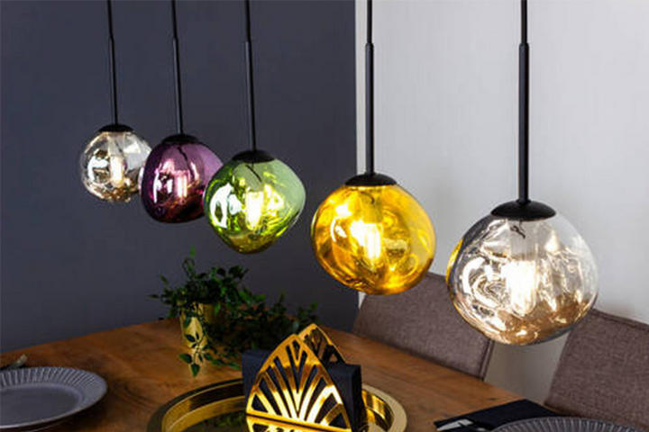Essbereich mit fünf bunten Kugel-Pendelleuchten über einem Holztisch, gedeckt mit Tellern und dekorativer Mitte.