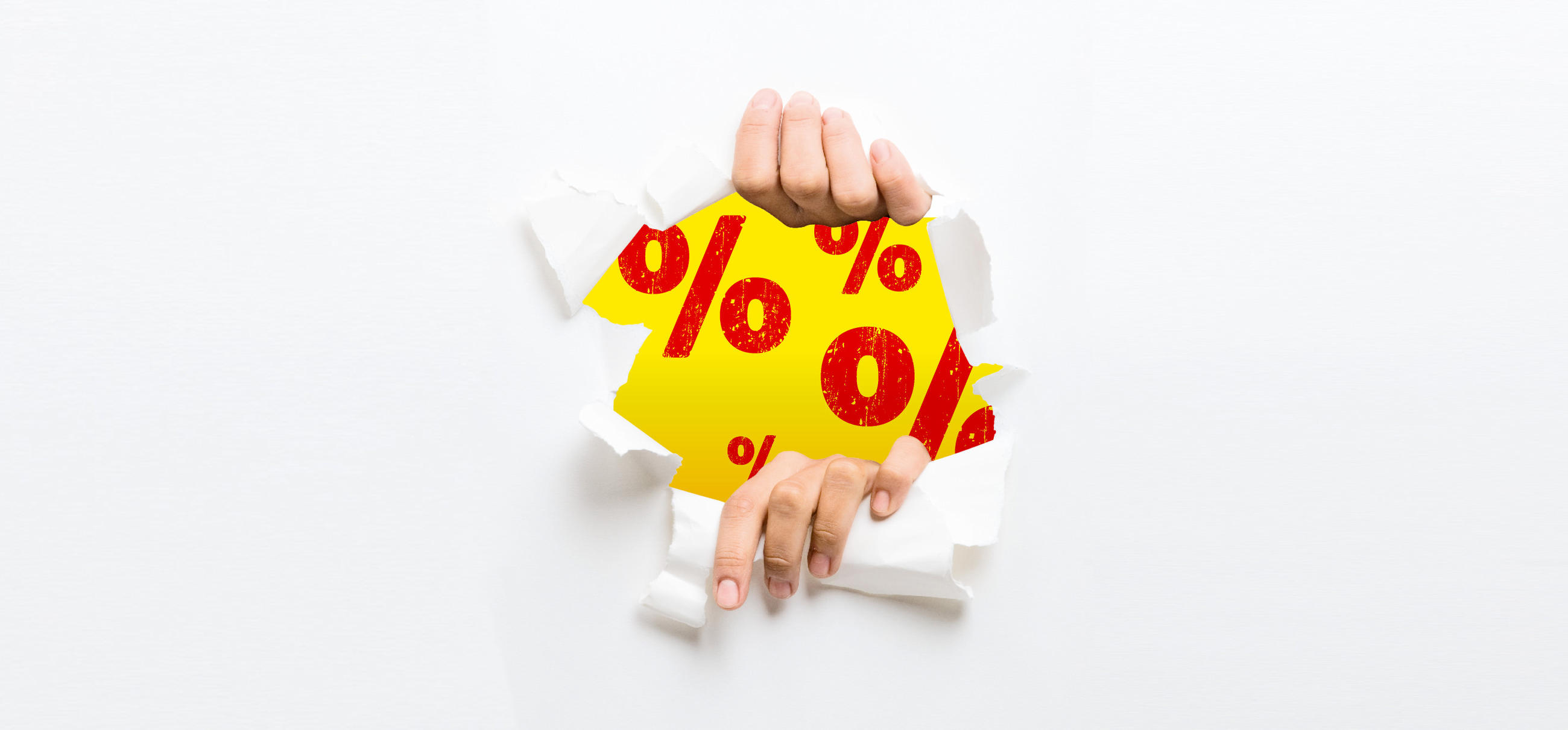 Online vypredaj, dve ruky trhajú biely papier, za papierom žlté pozadie s veľkými červenými znakmi %, akcia, zľava, ruky prerážajú bariéru, aby odhalili ponuku so zľavami