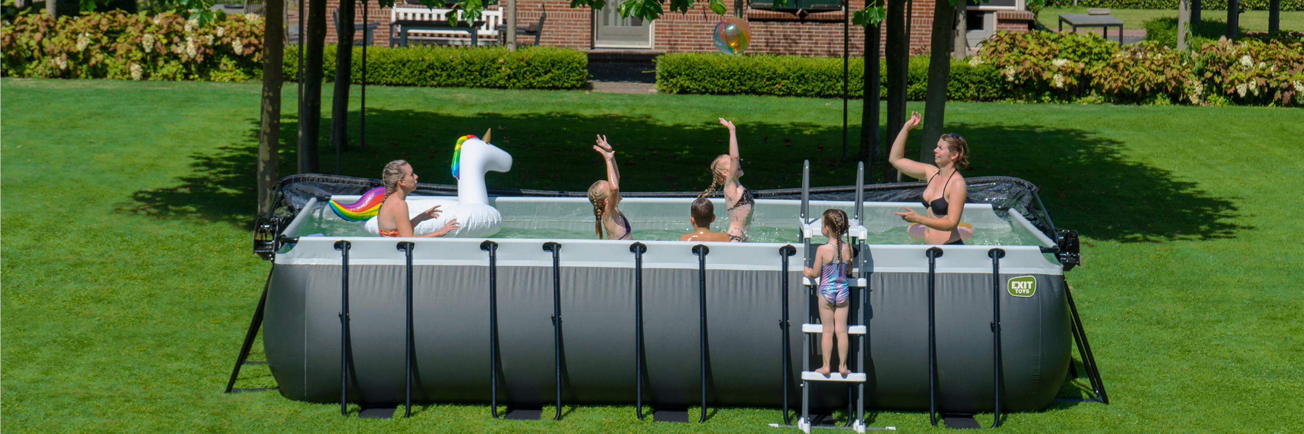 Ein grosser Pool in einem Garten mit einer Familie, die spielt