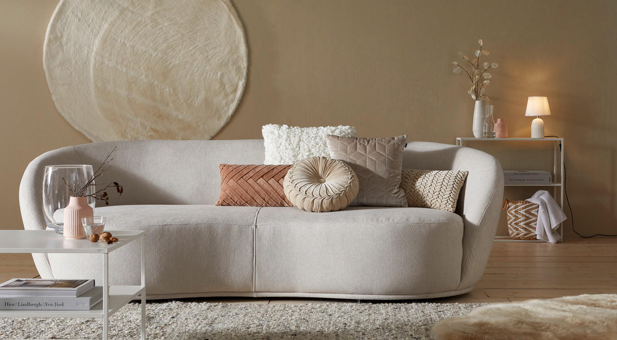 beige couch mit kissen, teppich und beistelltisch
