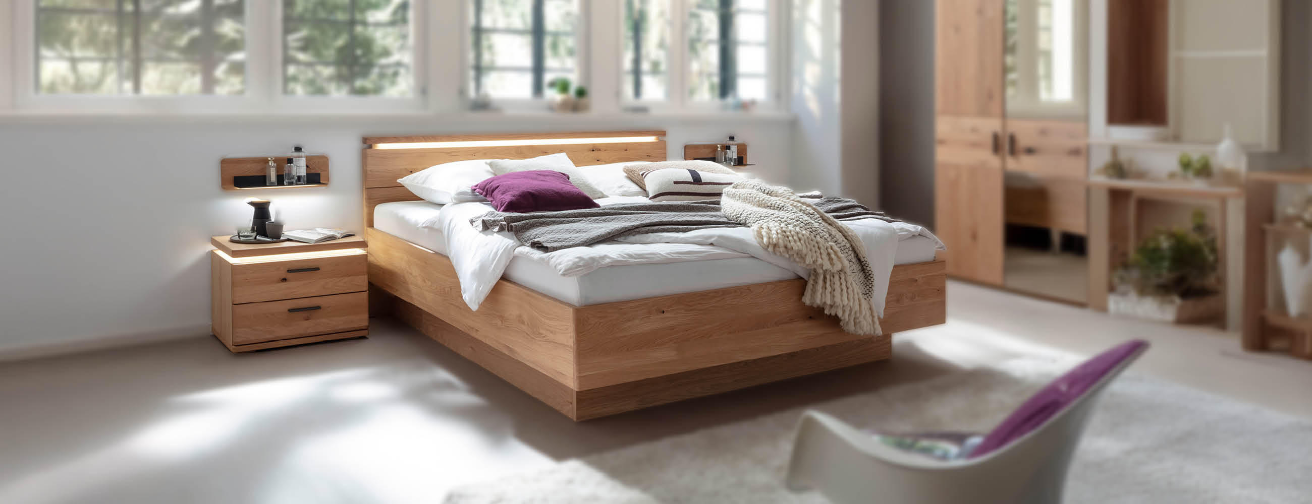 Ein Schlafzimmer mit einem Bett, einer Kommode und einem Kleiderschrank aus Holz mit integrierten LEDs..