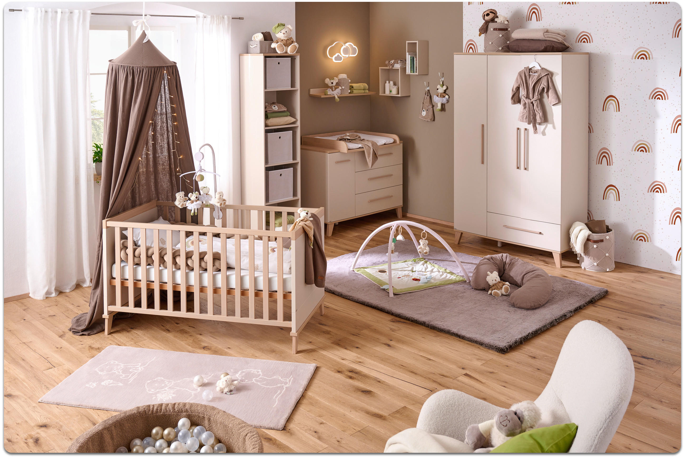 Kinderzimmer mit Babybett, Wickelkommode, Kleiderschrank, Spielmatte und Sitzsessel in hellen Holztönen und neutralen Farben.