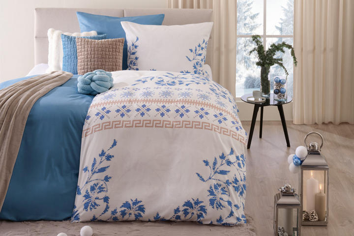 Bett in weiß, blau-weiße Bettwäsche und beige Vorhänge