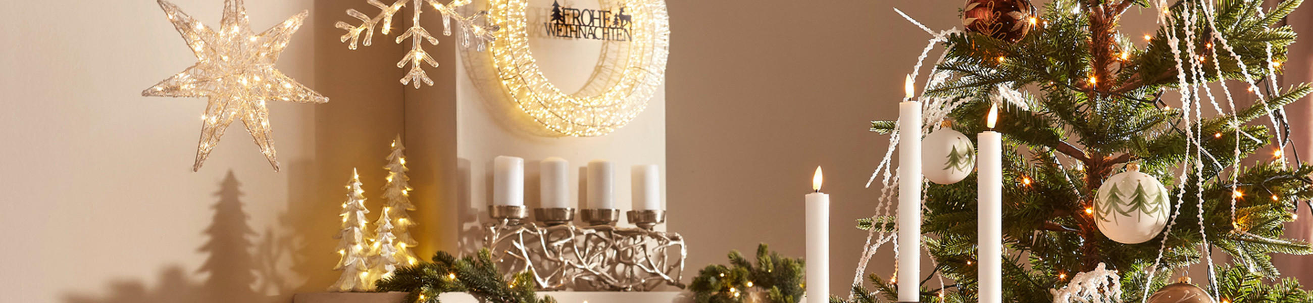 Adventskranz neben einem Weihnachtsbaum auf einer Kaminbank