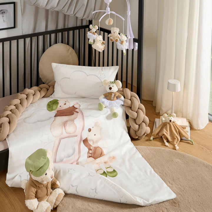 Otroška soba z posteljico, posteljo, medvedkom in odejo, opremljena za dojenčke.