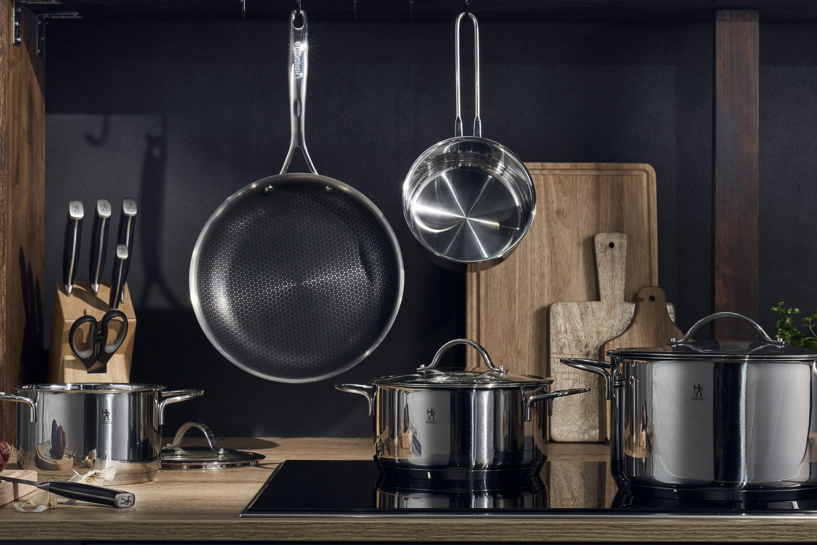 Nahaufnahme einer Arbeitsplatte mit hochwertige Pfannen, Töpfe und sonstige Küchenuntensilien der Marke Henckels by Zwilling