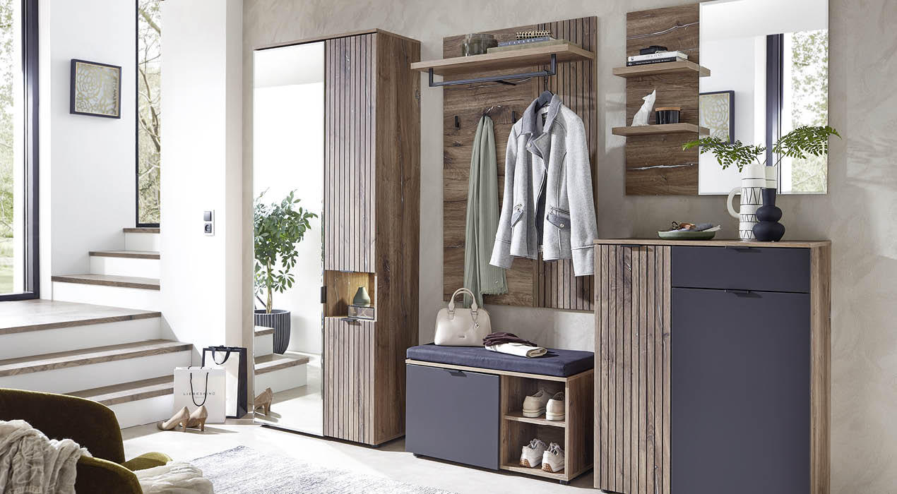 Stilvoller Eingangsbereich mit Holzmöbeln, darunter Garderobe mit Jacken, Sitzbank mit Stauraum, geriffeltem Hochschrank und dekorativer Kommode mit Pflanzen