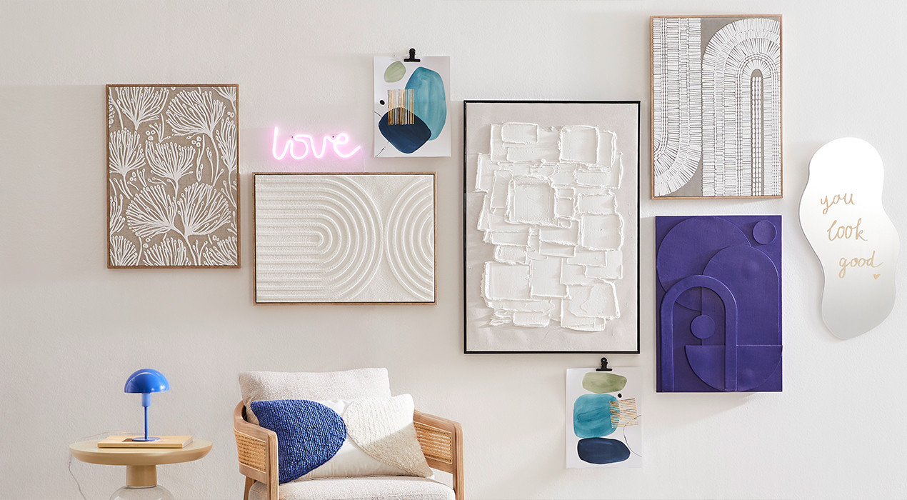 Eine weiße Wand, geschmückt mit einer Vielzahl von Kunstwerken, die unterschiedliche Stile und Farben präsentieren.