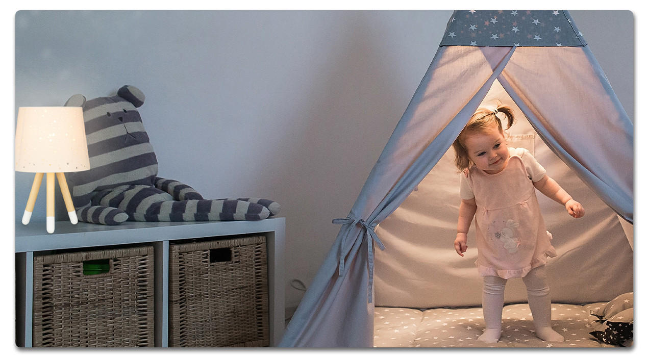 Baby in einem Spielzelt mit lampe auf der Kommode