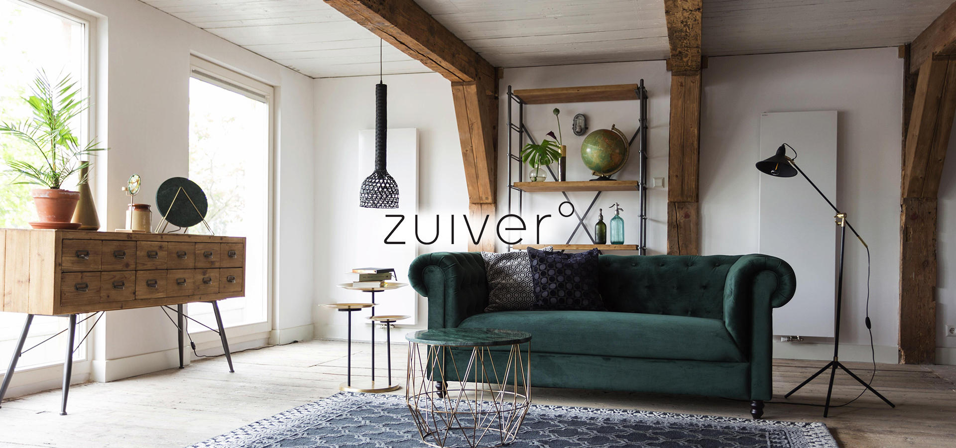 Abbildung eines Wohnzimmers mit grünem großen Sofa in Samtoptik in der Mitte von der Marke Zuiver