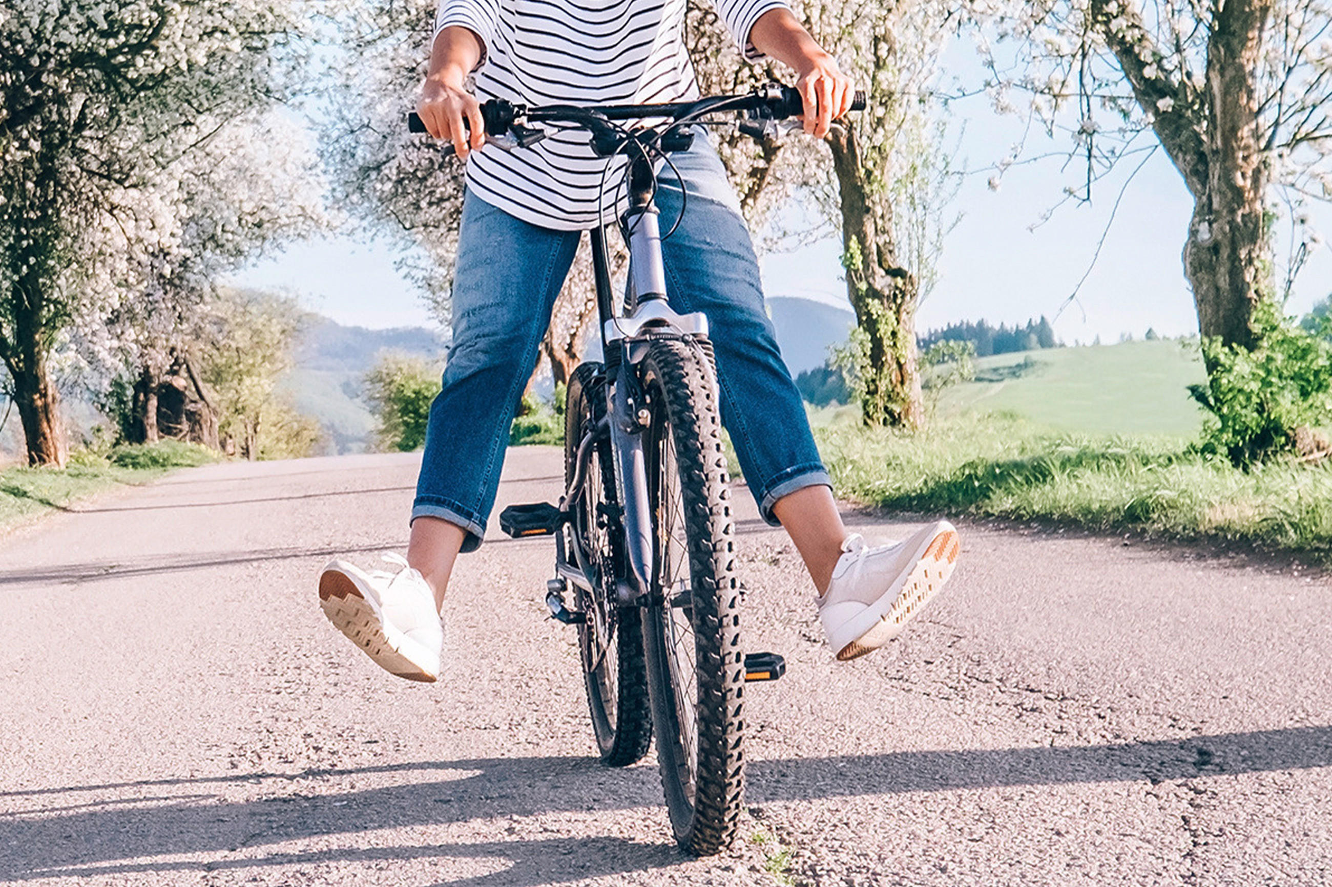 Eine Radfahrerin auf einer Landstraße, die sicherstellt, dass ihre Fahrradbremsen funktionieren.