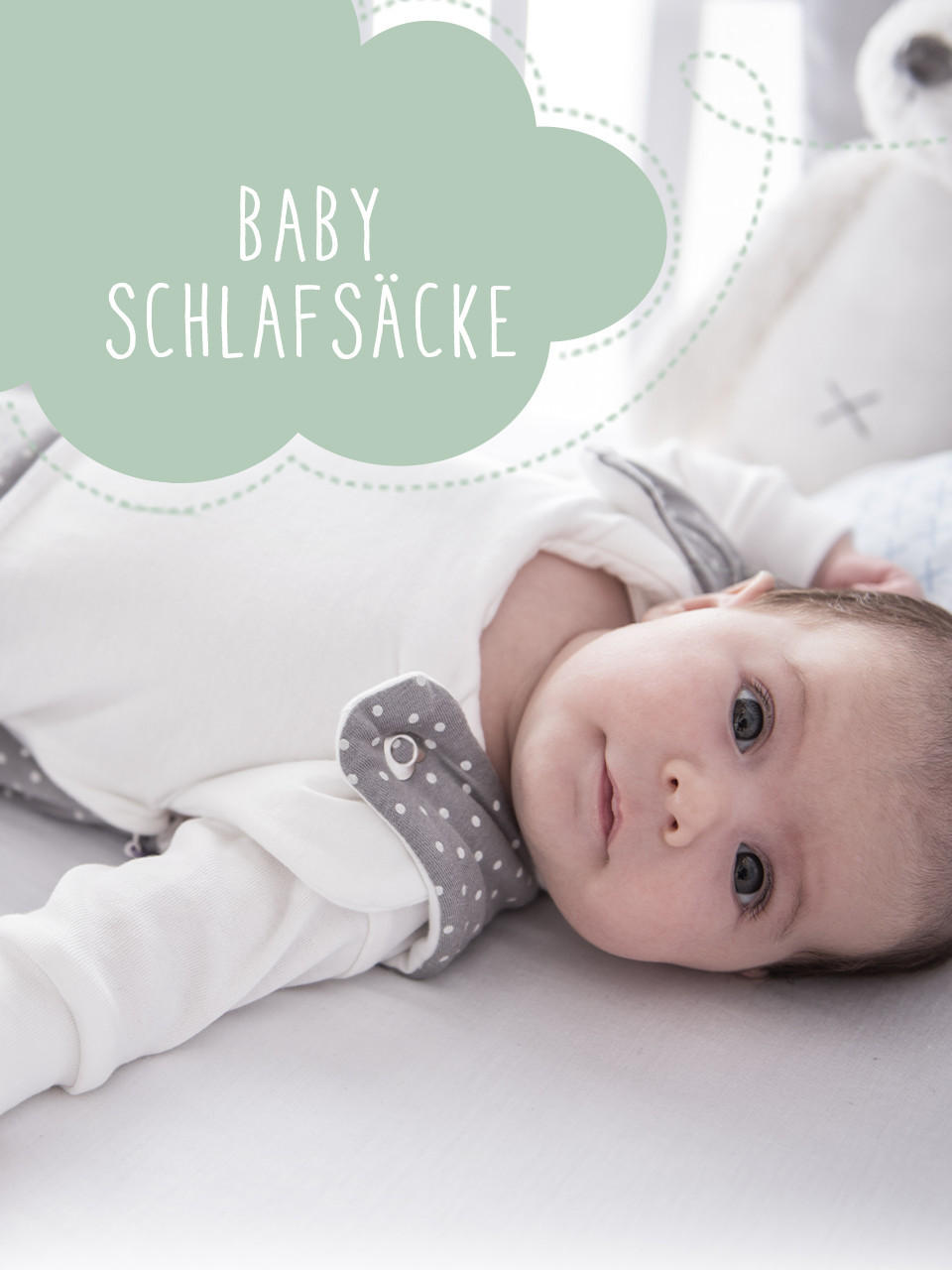 baby liegt im grauen Schlafsack auf dem Bett