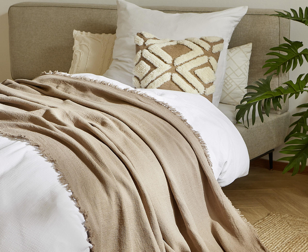Bett sommerlich dekoriert in beige Tönen