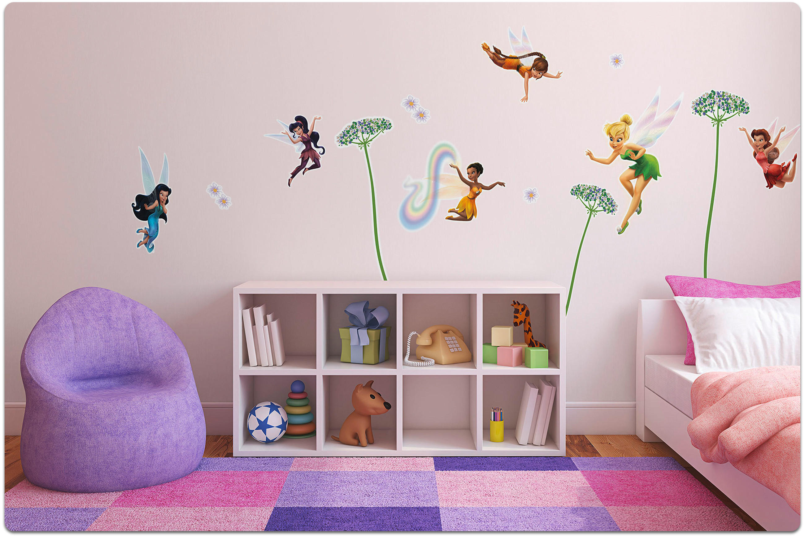 Kinderzimmer mit lila Sitzsack, weißem Regal mit Spielzeug und Büchern, Wand mit Feen- und Blumenaufklebern, bunter Teppich und Bett mit rosa Decke.