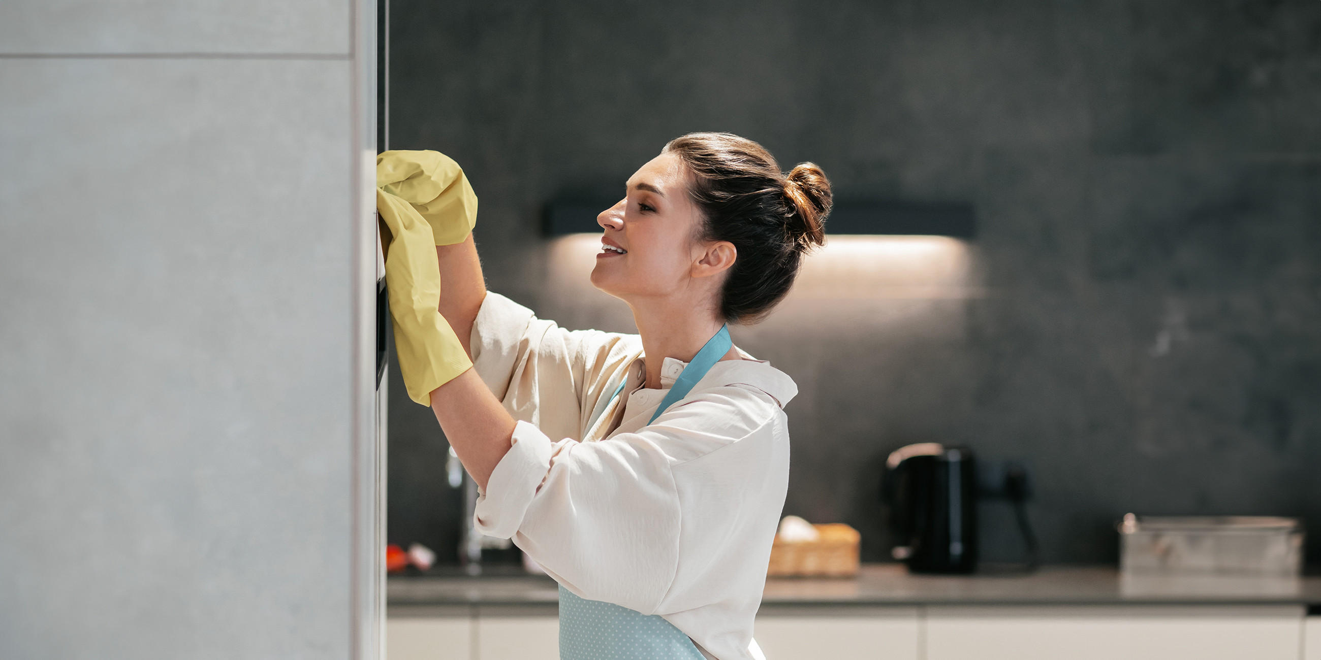 Küchenratgeber: Kühlschrank reinigen, Junge Frau mit Handschuhen putzt