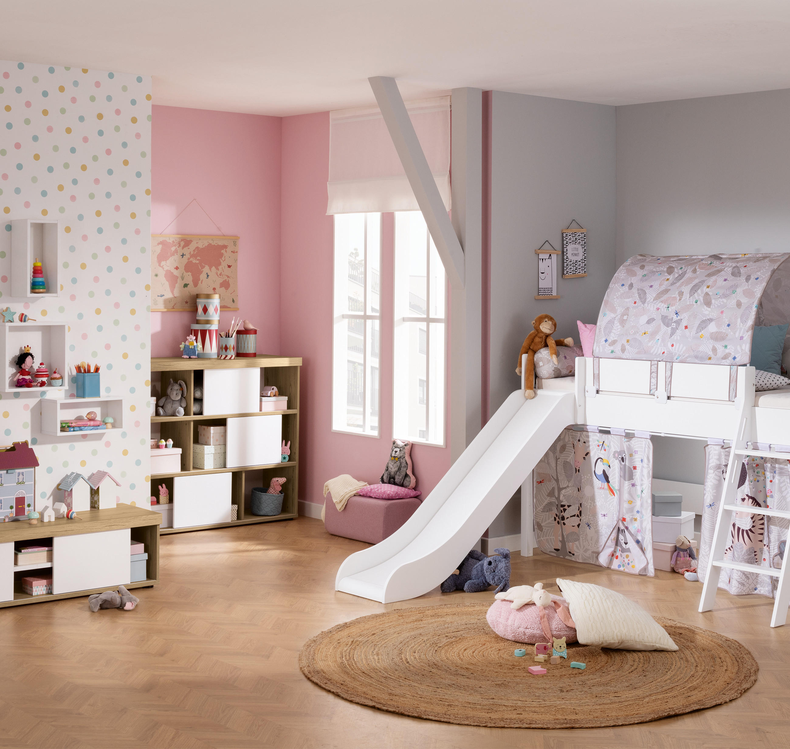 Kinderzimmer mit Hochbett inklusive Rutsche, Spielzelt und Leiter sowie Regalen mit Spielzeug vor einer gepunkteten Wand.