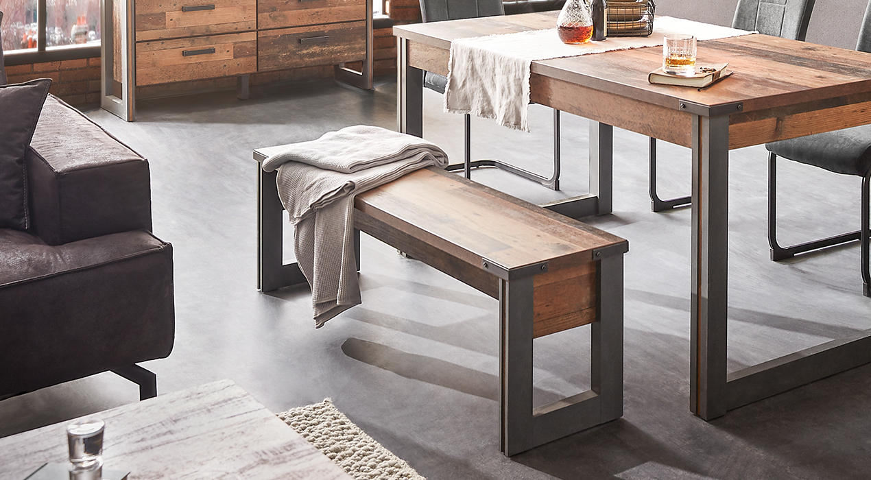 Sitzbank aus Holz mit gepolstertem Kissen, platziert in einem hellen Wohnbereich mit gemütlicher Einrichtung und dekorativen Elementen