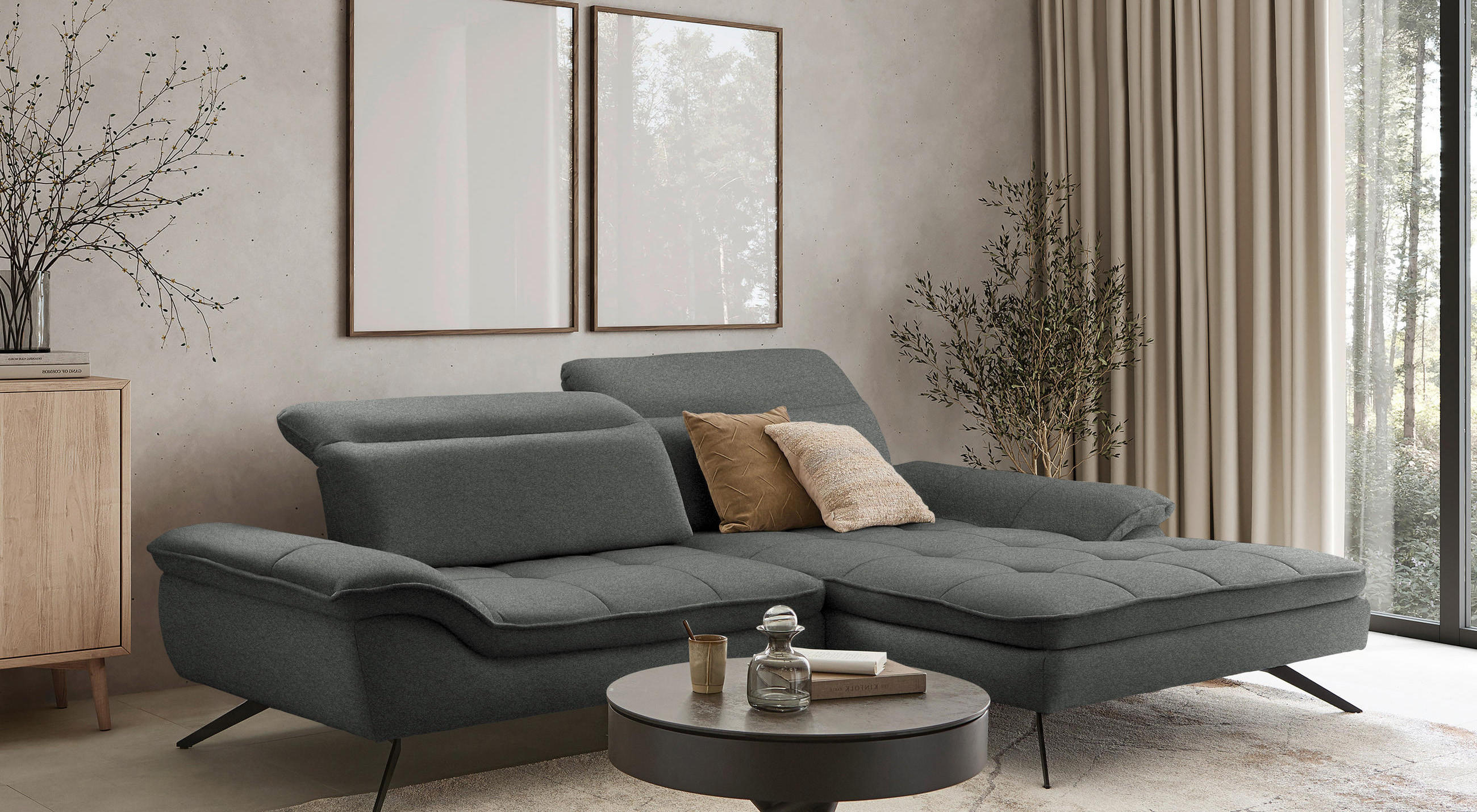 Ecksofa in dunkelgrau mit beigen Bildern an der Wand, beigen Vorhängen und dunklem Couchtisch.