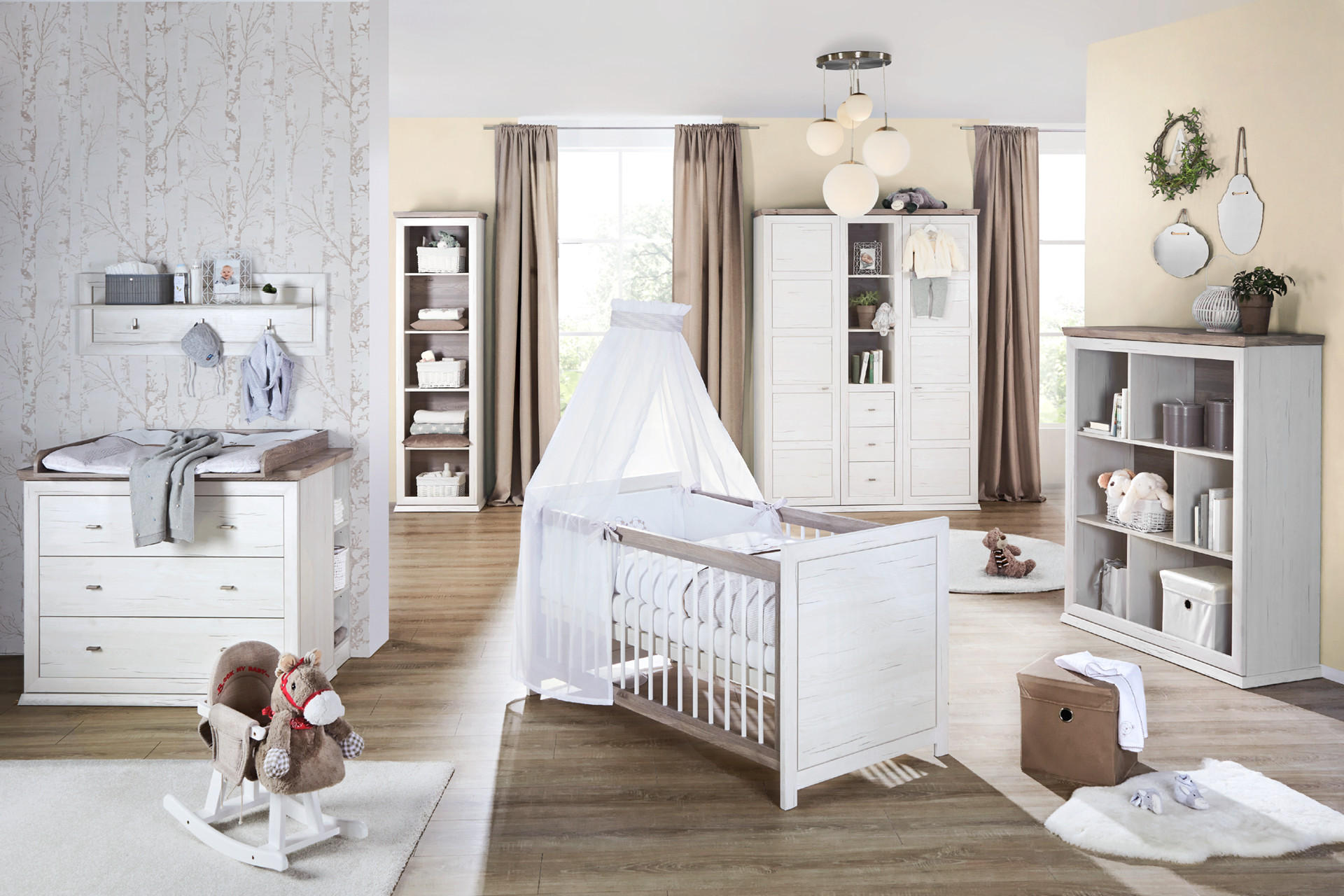 Babyzimmer im Landhausstil mit Gitterbett, Kästen und Schaukelpferd in hellgrau/beige