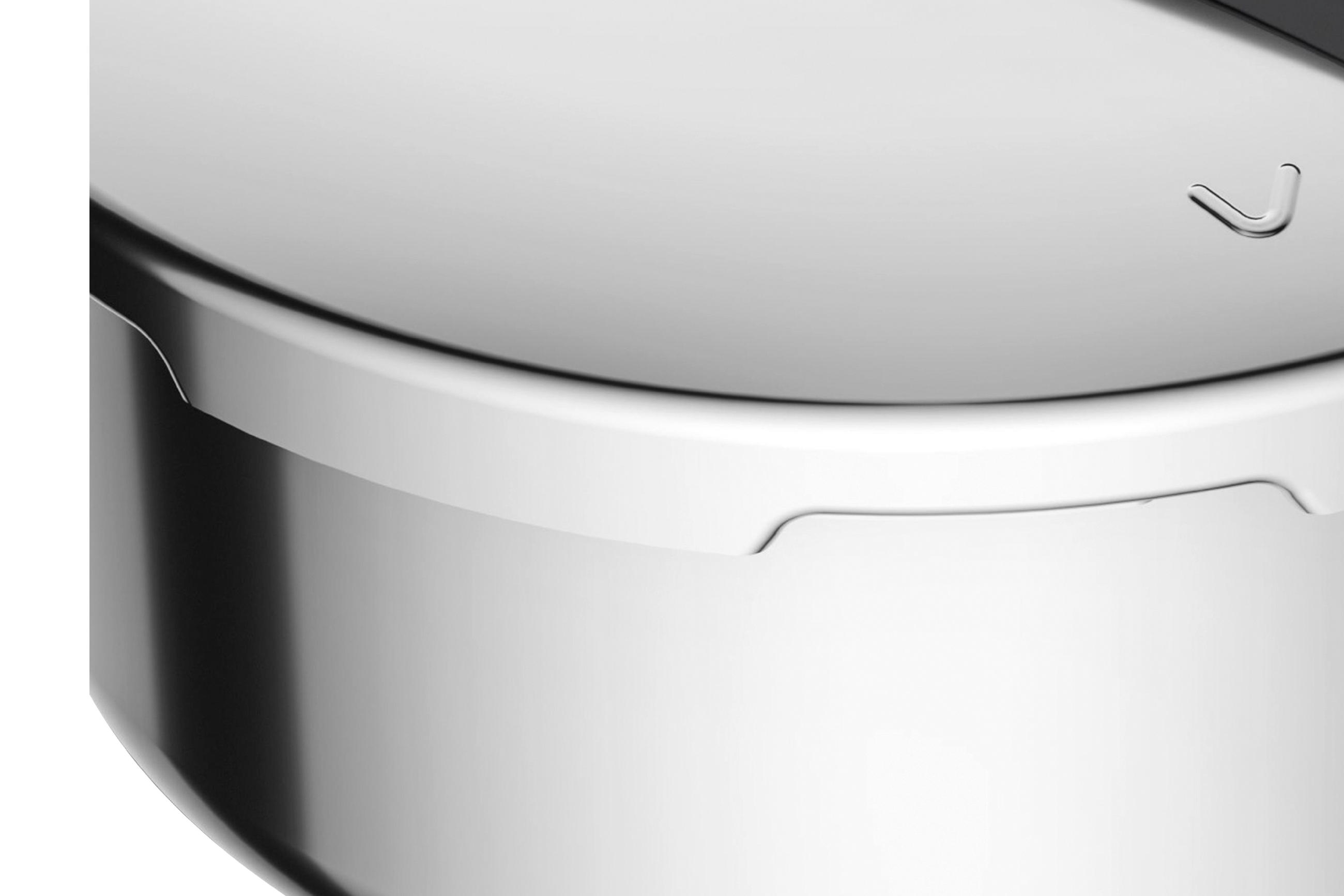 Närbild av en tryckkokares rostfria stålkärl med ett lock som har en diskret ingraverad symbol.