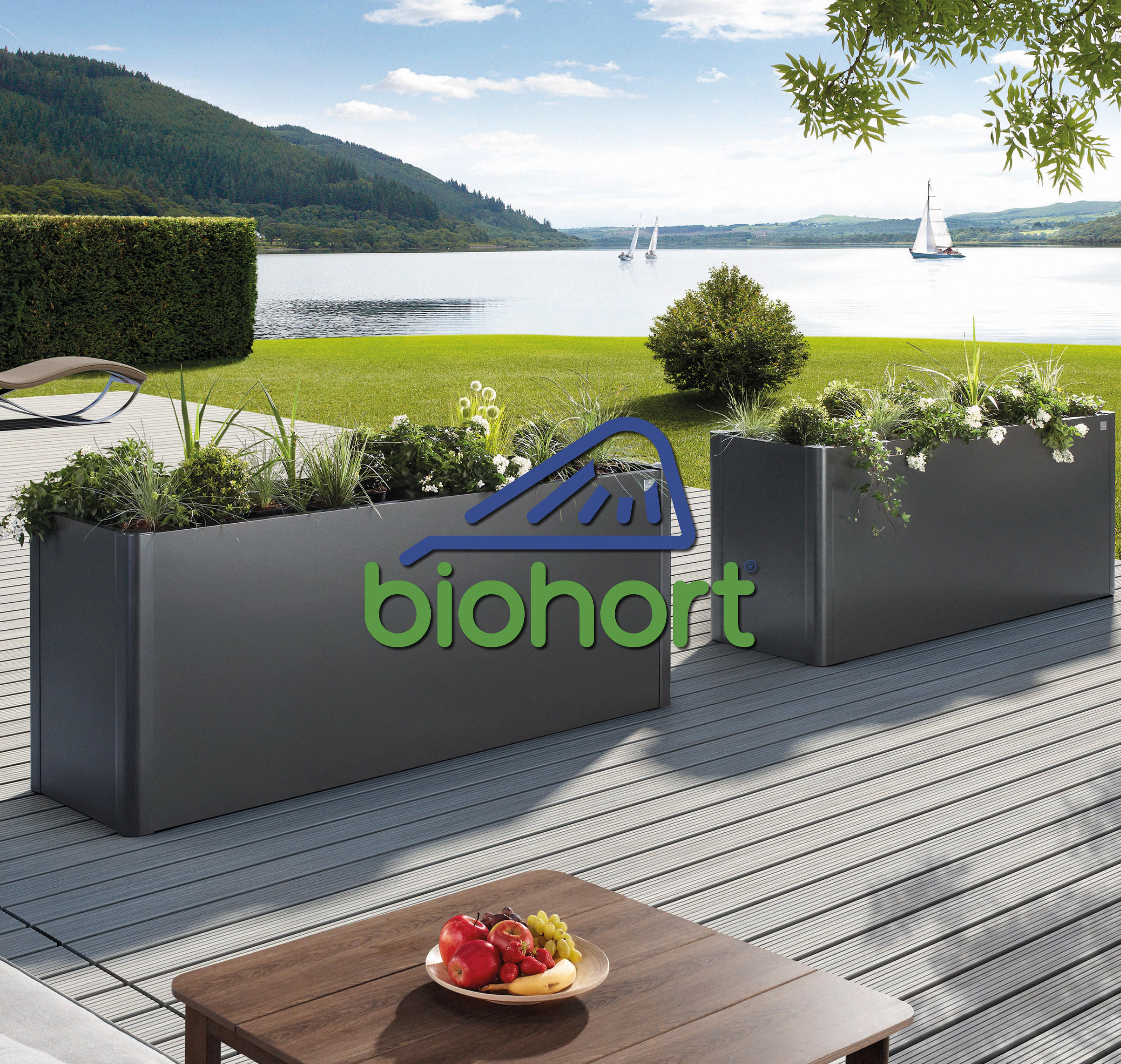 Biohort Hochbeete in Aluminium-grau auf einer sonnigen Terrasse vor einer grünen Wiese und einem See