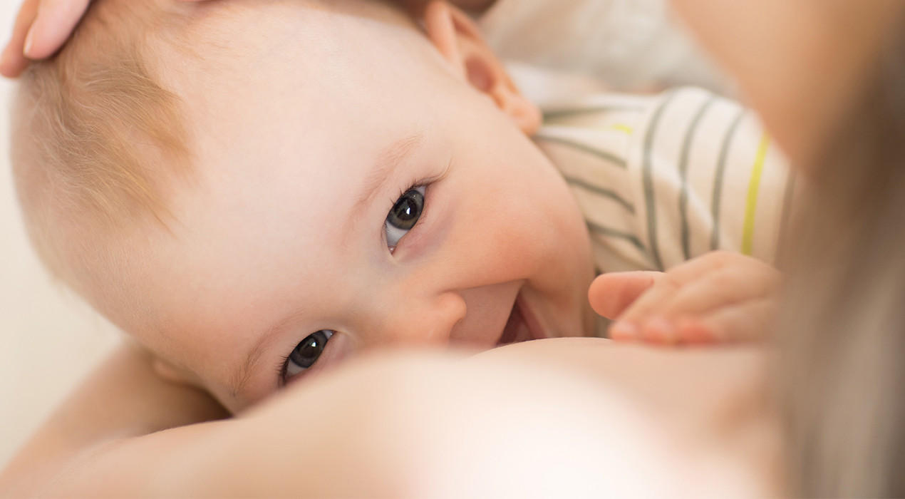 baby wird auf dem Arm einer Frau gestillt